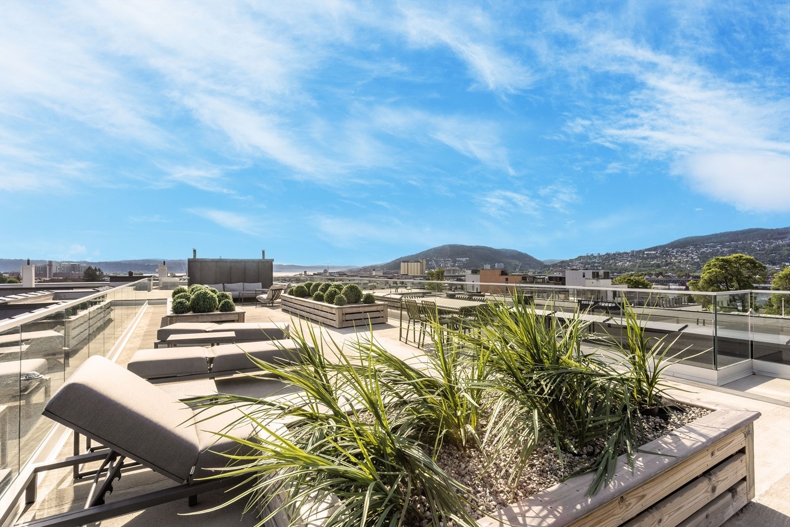 Terrassen er pent beplantet og møblert med solsenger, spisebord og sofagruppe. Galleribilde