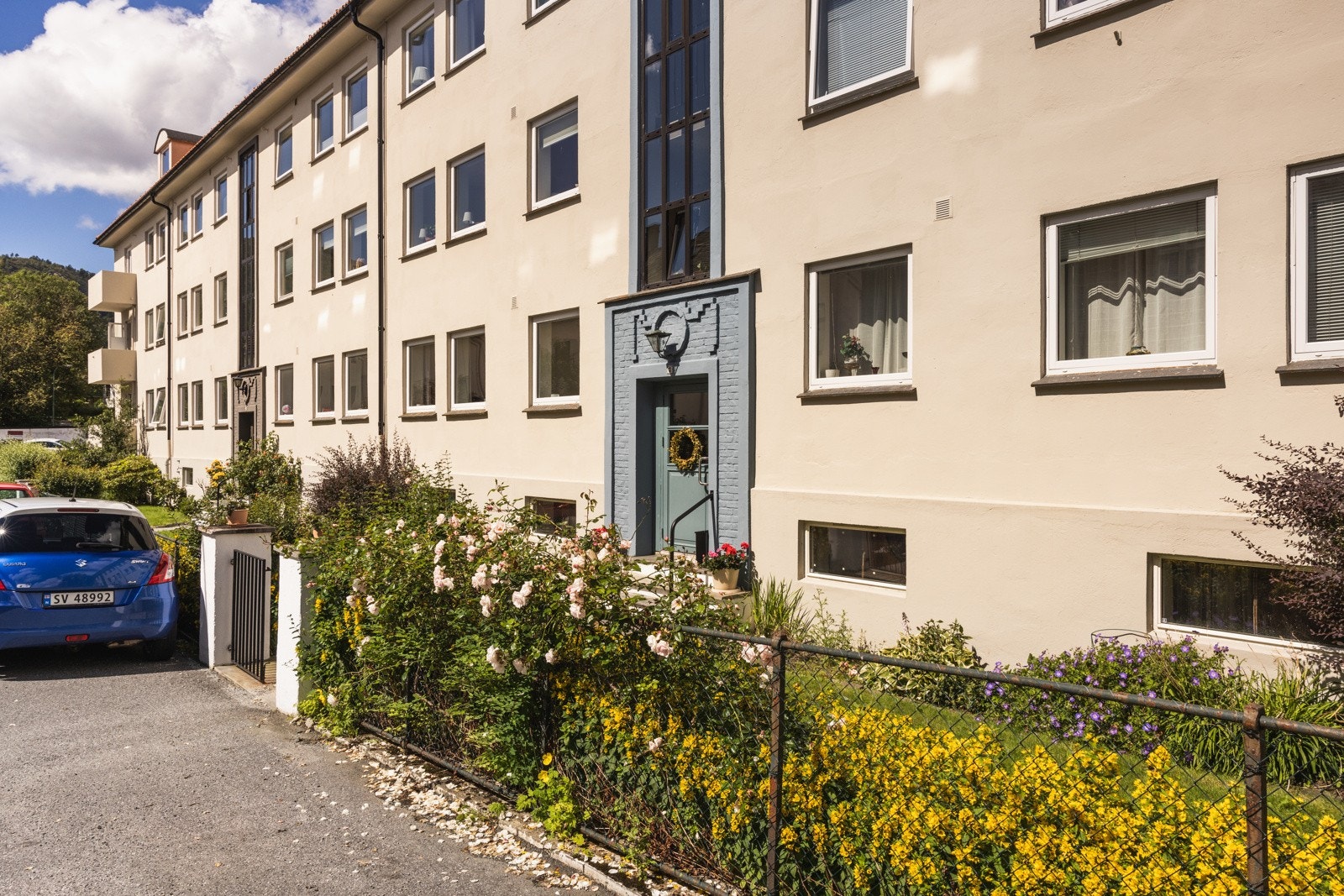 På forsiden er det solrik forhage med fine blomsterbed. Galleribilde