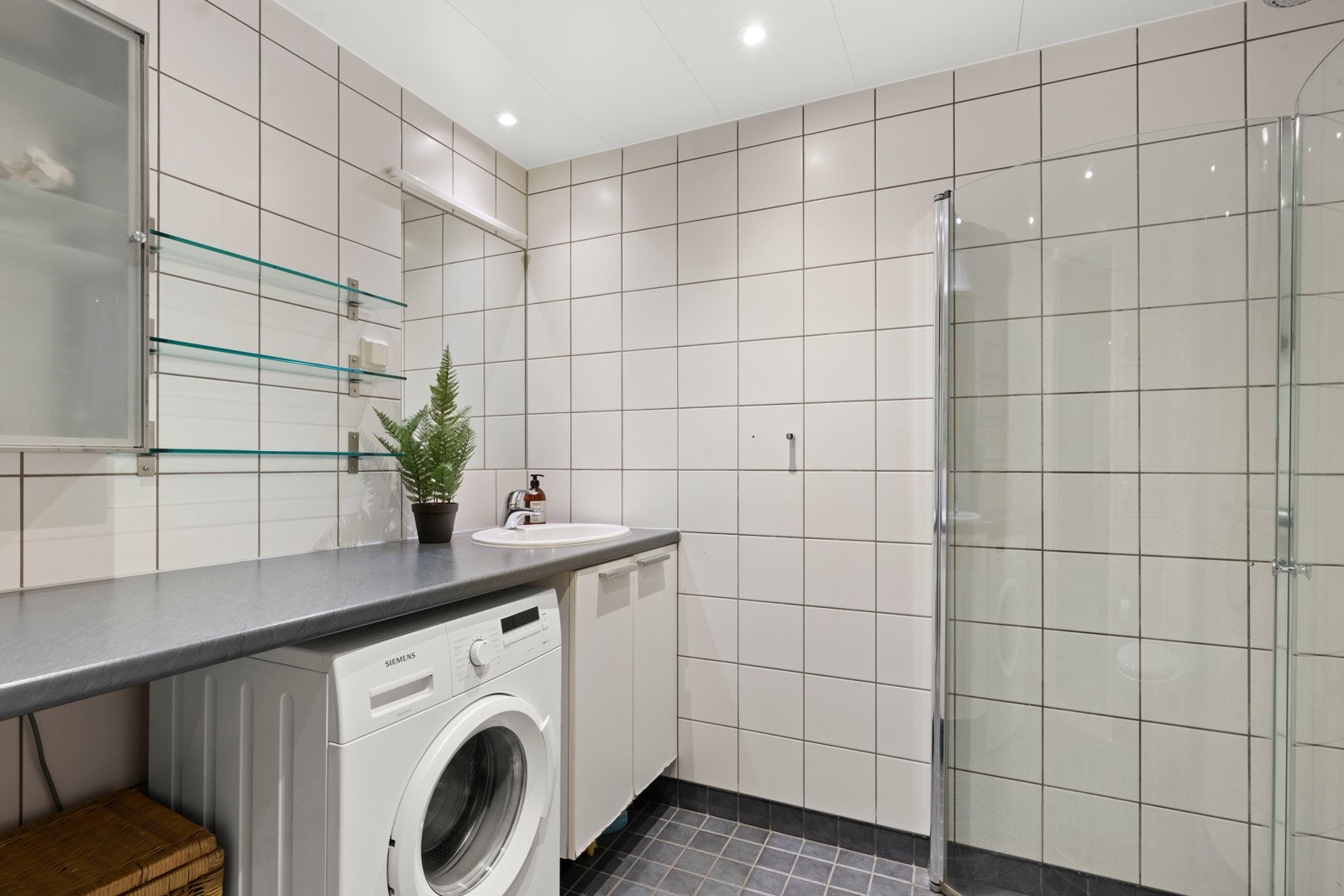 Pent baderom fra 2007 med god størrelse. Badet består av vegghengt toalett, dusjhjørne med to svingbare glassdører og opplegg for vaskemaskin. Innredningen har slette fronter. Galleribilde