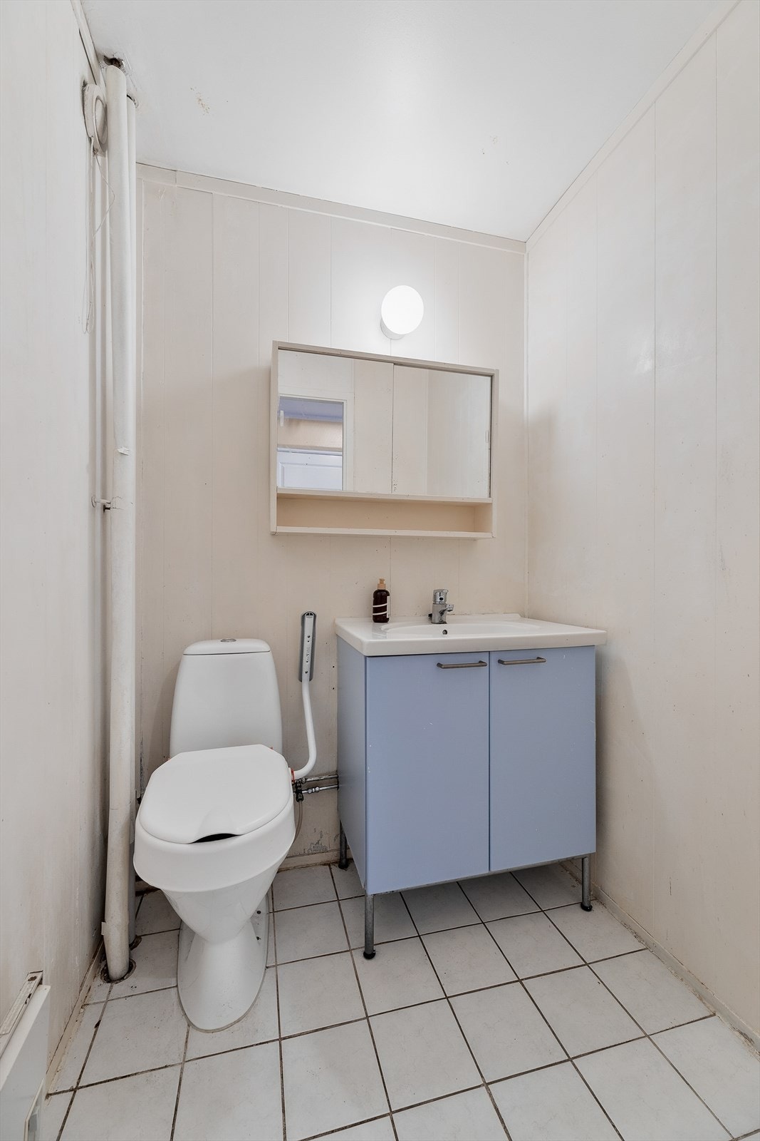 Separat wc-rom med flislagt gulv, utstyrt med gulvstående wc og servantinnredning med underskap. Galleribilde