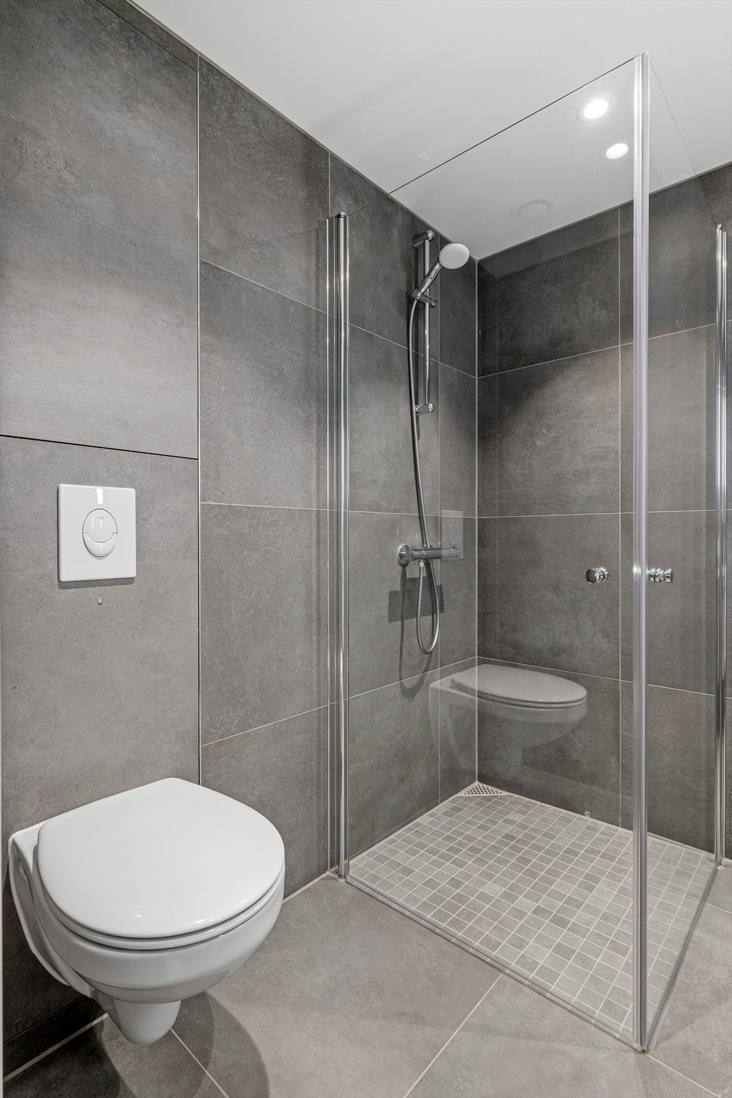 Vegghengt wc, sammenslåbare dusjdører og vannledninger som er skjult bak flisene i et skap med softclose-funksjon, gir badet en stilren utførelse. Galleribilde