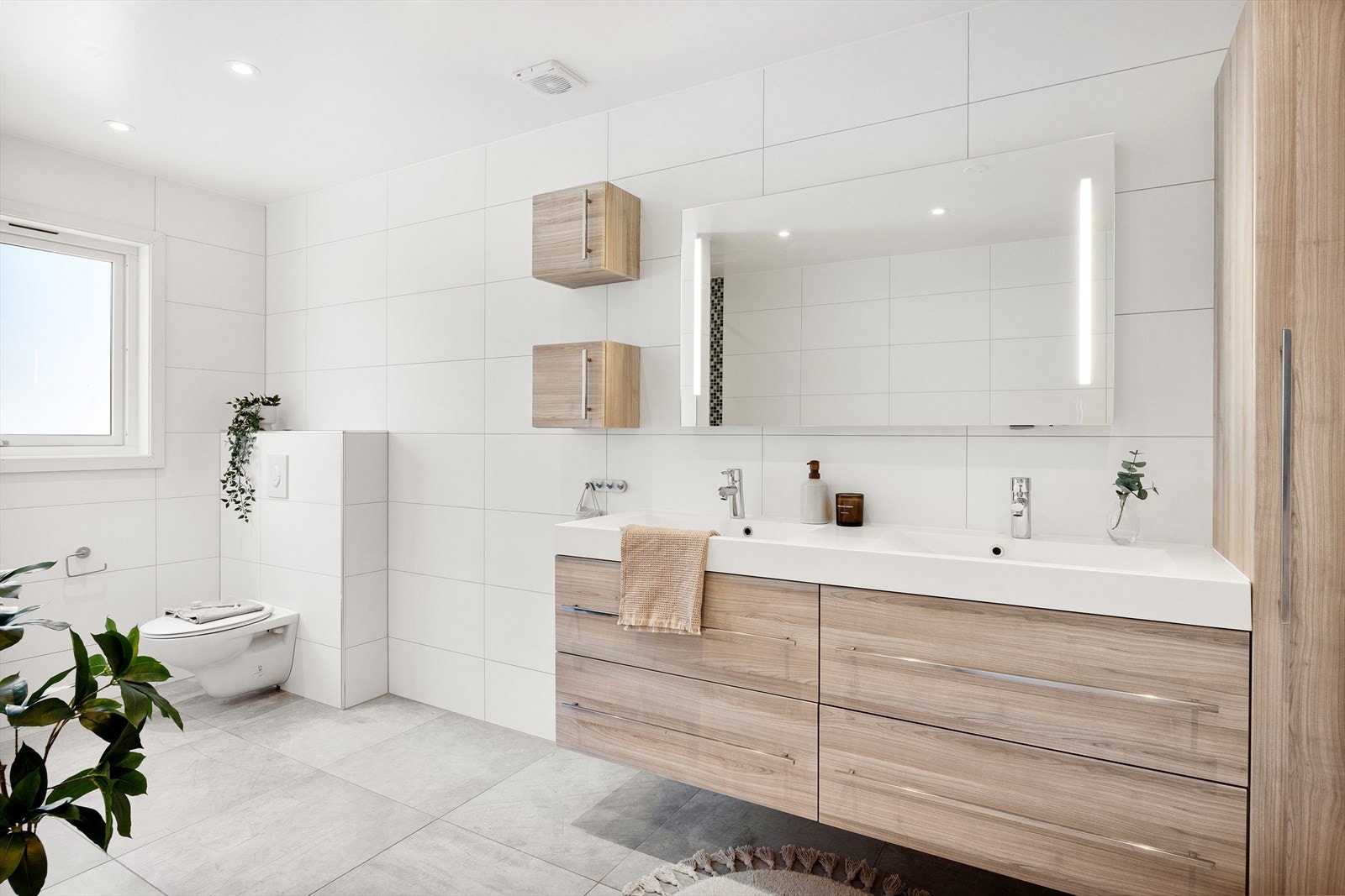 Badet er innredning med nedfelt servant, badekar, veggmontert toalett og 2 stk dusj i nisje Galleribilde