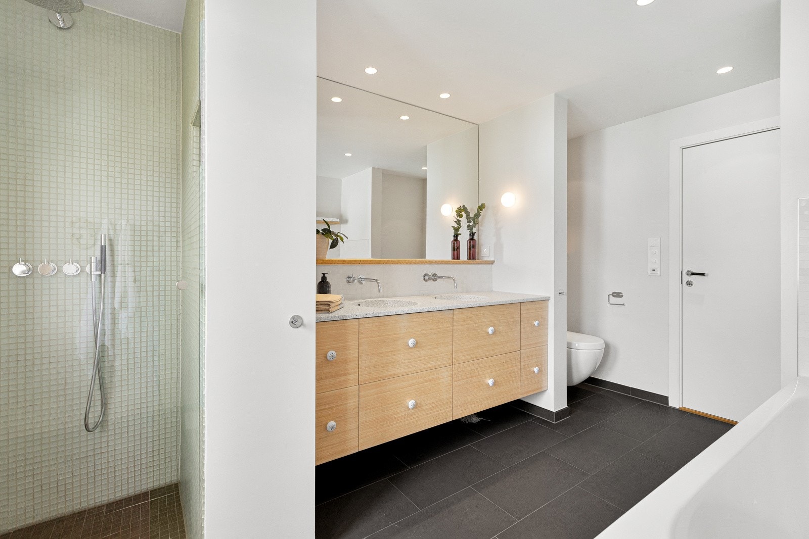 Badet i 1. etasje ble pusset opp i 2012, og har mørke fliser på gulv med varme, lyse overflater og i dusjen er det fliser i glassmosaikk. Galleribilde