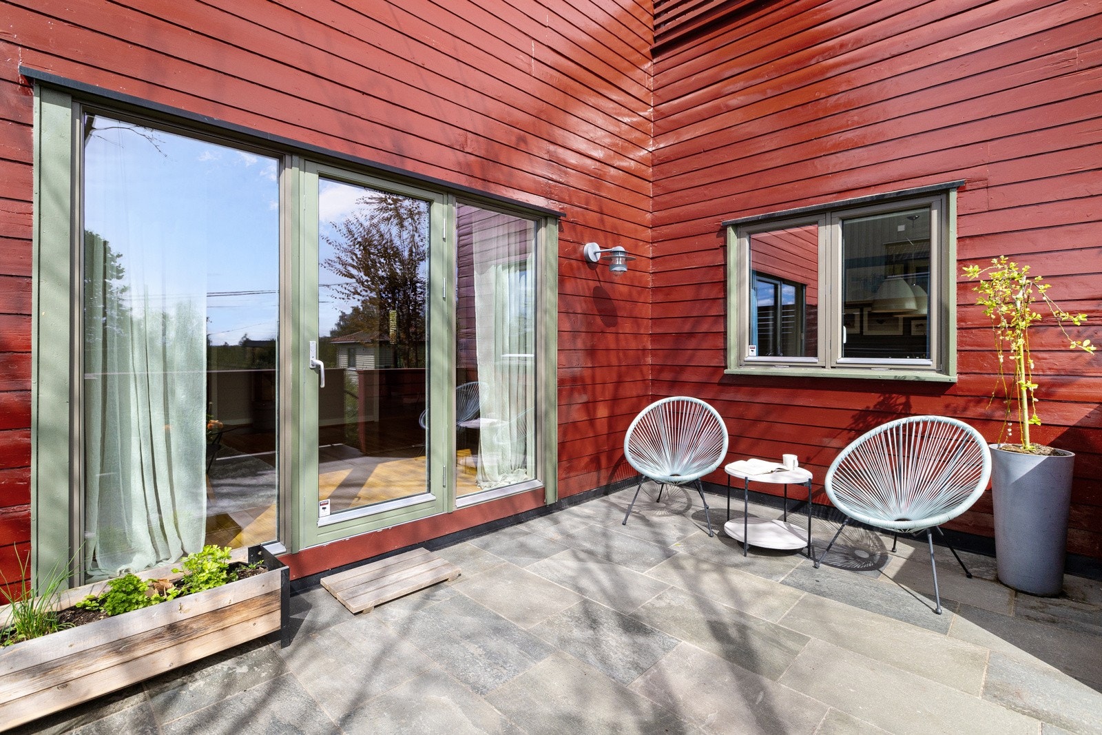 Sør- og vestvendt terrasse i trekonstruksjon på ca. 17 kvm med skifer på dekke og rekkverk i malt treverk. Her er det god plass til både grill, sittegruppe og planter. Galleribilde