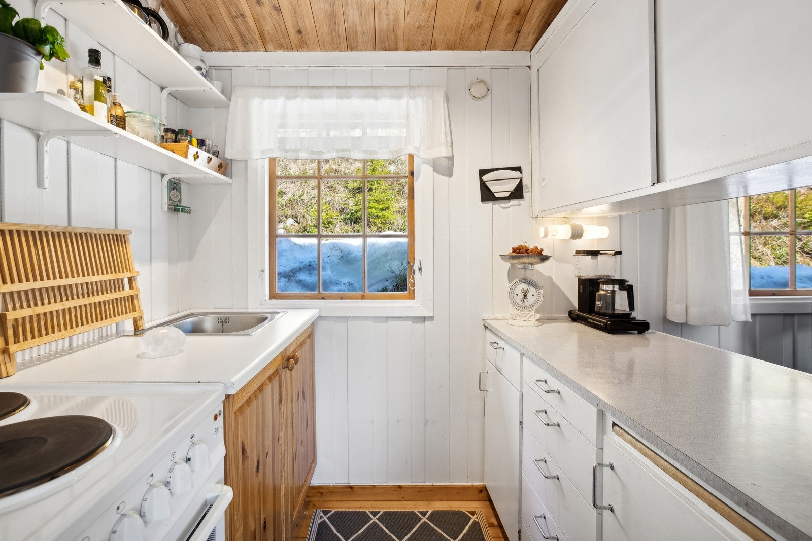 Kjøkkeninnredning med profilerte og glatte fronter, benkeplater i laminat og oppvaskkum. Kjøkkenet har plass til frittstående komfyr og kjøleskap. Galleribilde