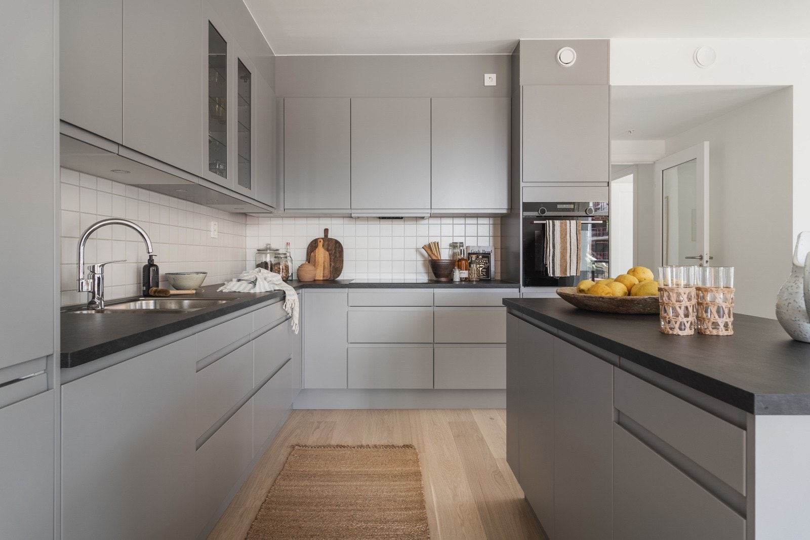 Kjøkkeninnredningen fra Sigdal i Horisont Palett med kullfarget laminat benkeplate og slette fronter med innfreste grep, gir et moderne og stilrent design. Galleribilde