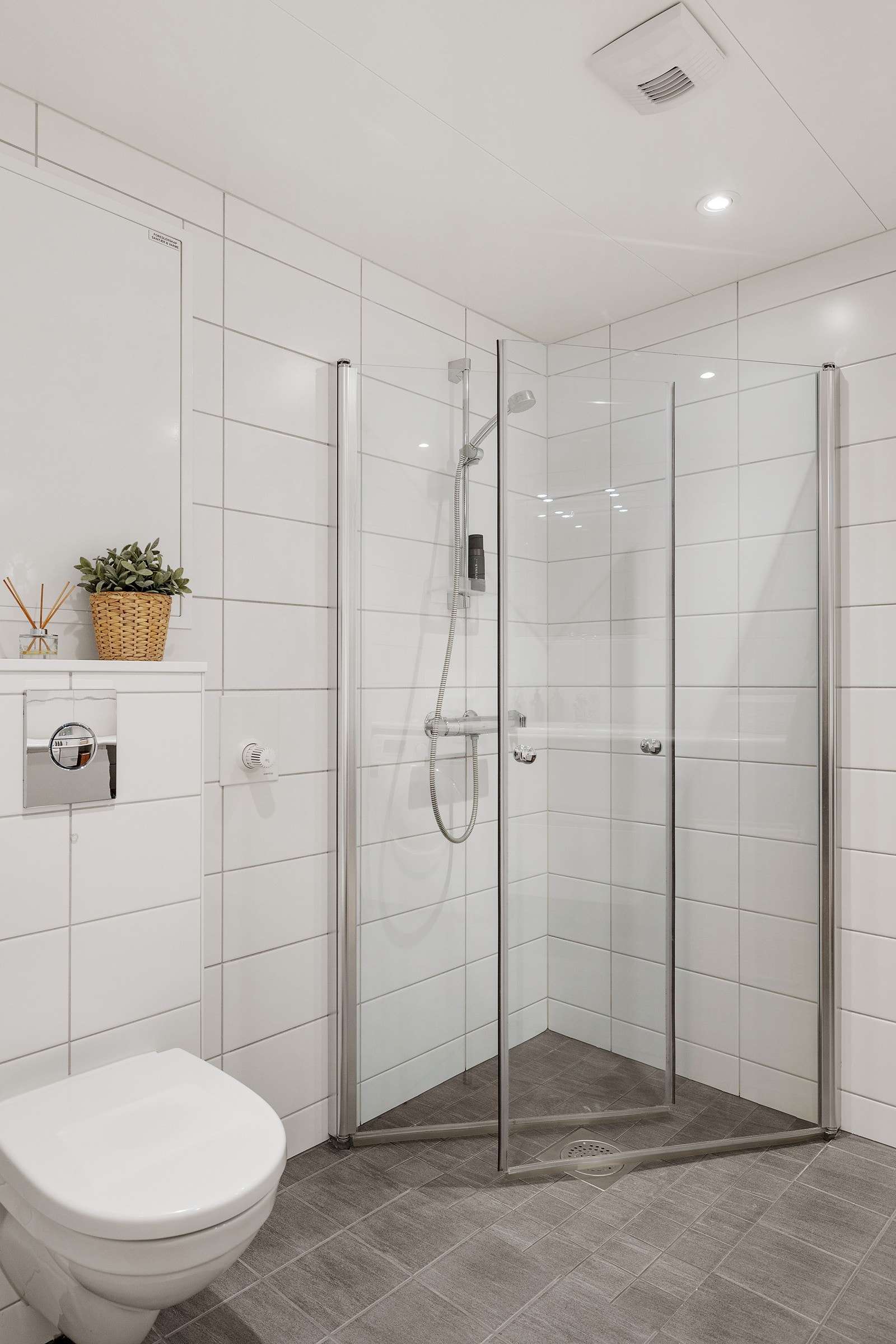 Videre er badet innredet med vegghengt toalett og dusjhjørne med plassbesparende og innfellbare glassdører. Galleribilde