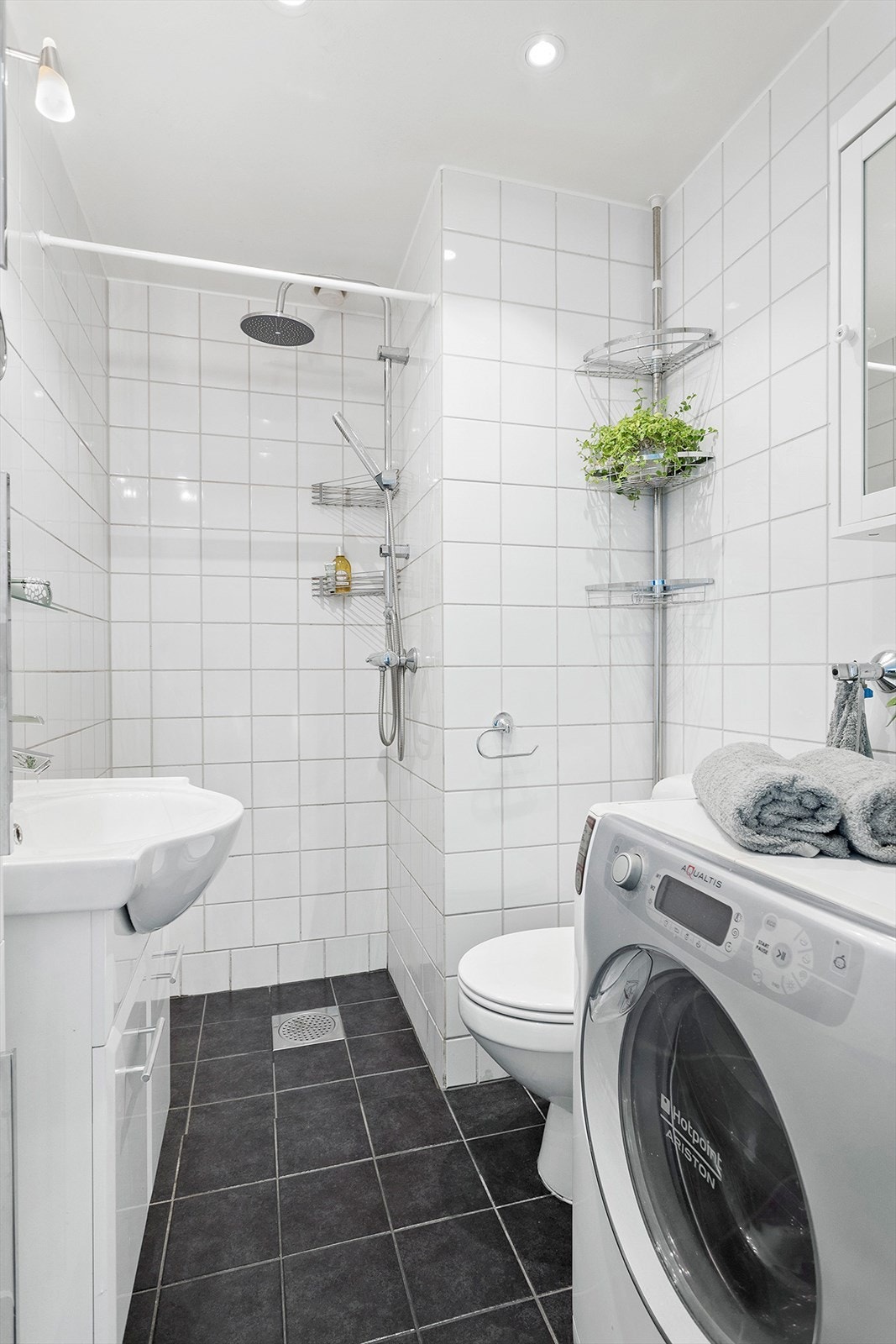 Badet er flislagt med varmekabler i gulv. Dusjsone, servant, speil, toalett og opplegg for vaskemaskin Galleribilde