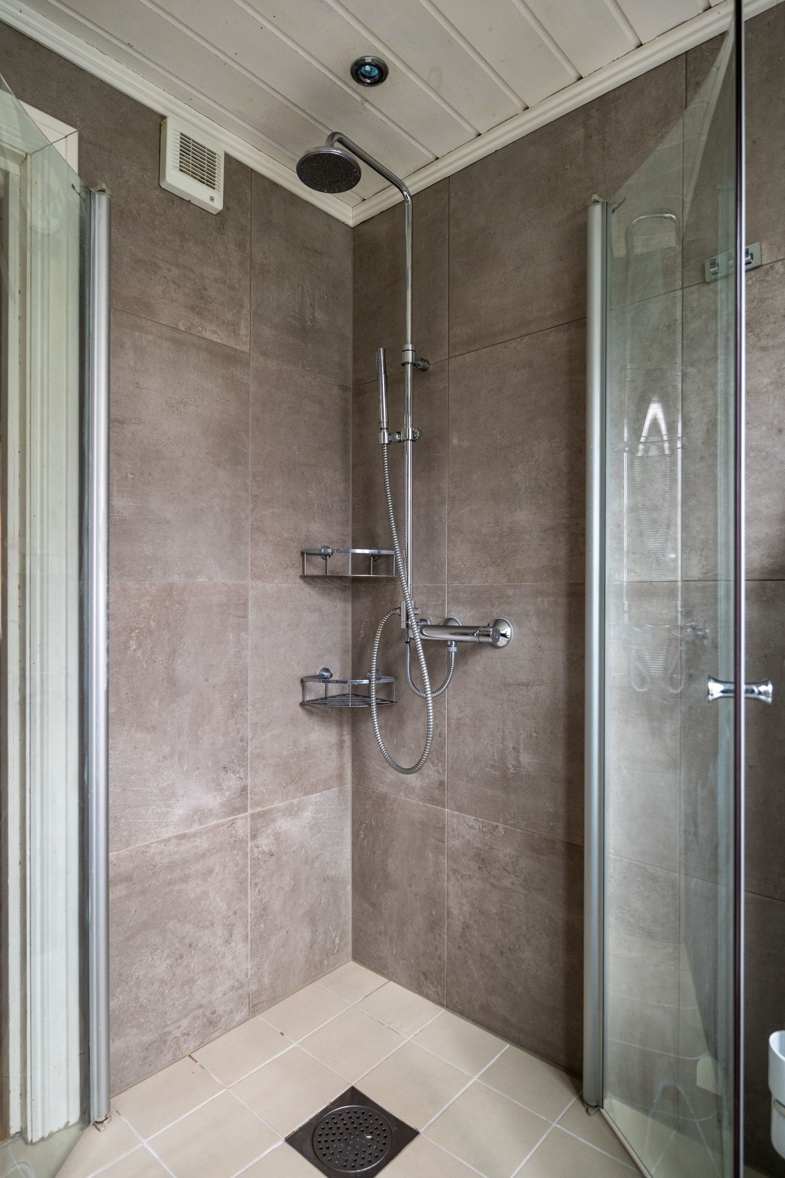 Dusjhjørne med innfellbare glassdører. Dusjarmatur tilkoblet regndusj og hånddusj. Galleribilde