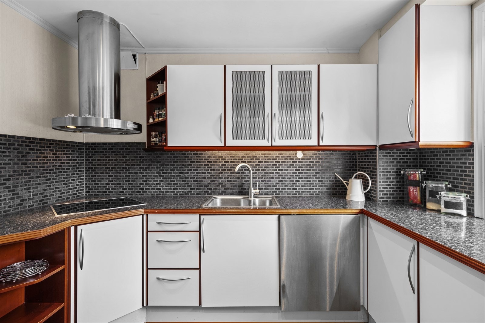 Kjøkkeninnredning består av glatte, folierte fronter, laminat benkeplate med nedfelt kum i rustfritt stål, lys under overskap, fliser på vegg over benkeplaten. Galleribilde