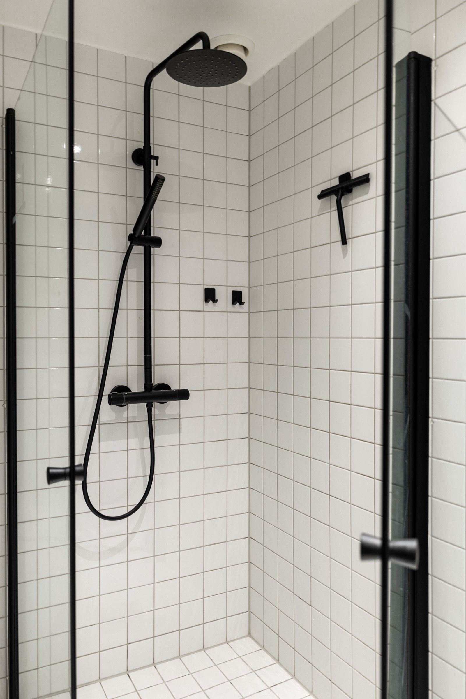 Dusjhjørne med innfellbare dører og dusjarmatur tilkoblet hånddusj og regndusj. Galleribilde