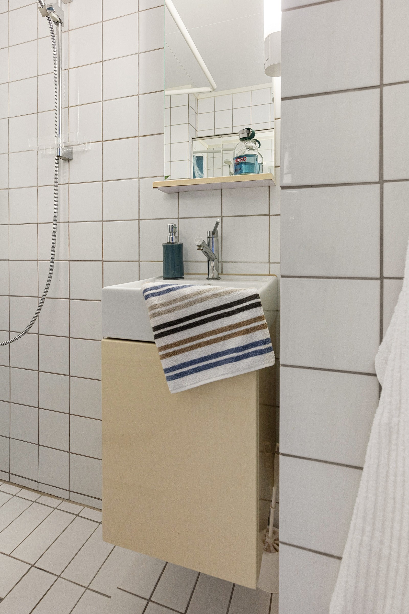 Baderomsinnredning med heldekkende servant, ett-greps blandebatteri og speil med belysning. Galleribilde