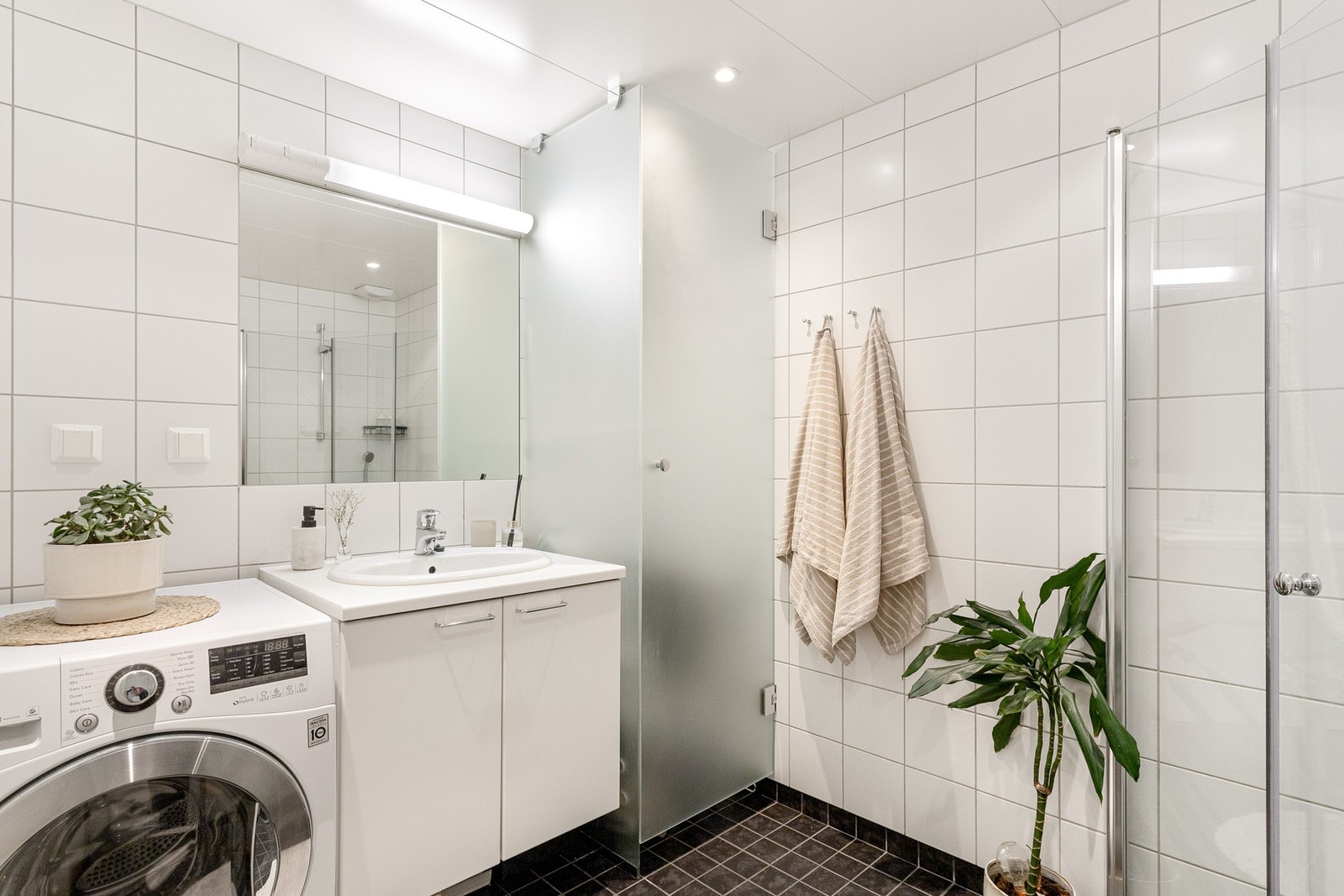 Badet er utstyrt med innredning med nedfelt servant, veggmontert toalett og dusjvegger/hjørne. Galleribilde