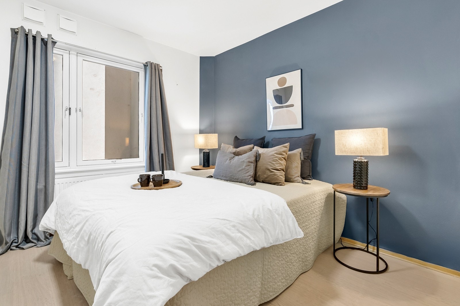 Soverom med god plass til dobbeltseng og nattbord på begge sider som vender inn mot byggets grønne patio. Galleribilde