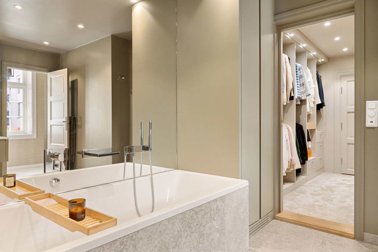 Badet er smakfullt innredet med vakre fliser og har en moderne dobbel servant som gir god plass for to. Speilet med innebygget belysning og de elegante armaturene gir badet et luksuriøst preg. Galleribilde
