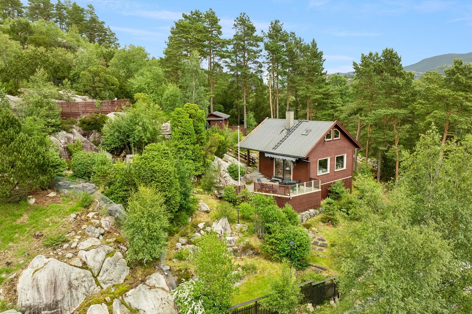 Eiendommen er en skrånet naturtomt med terrasse/platting på bakke på flere nivå. Galleribilde