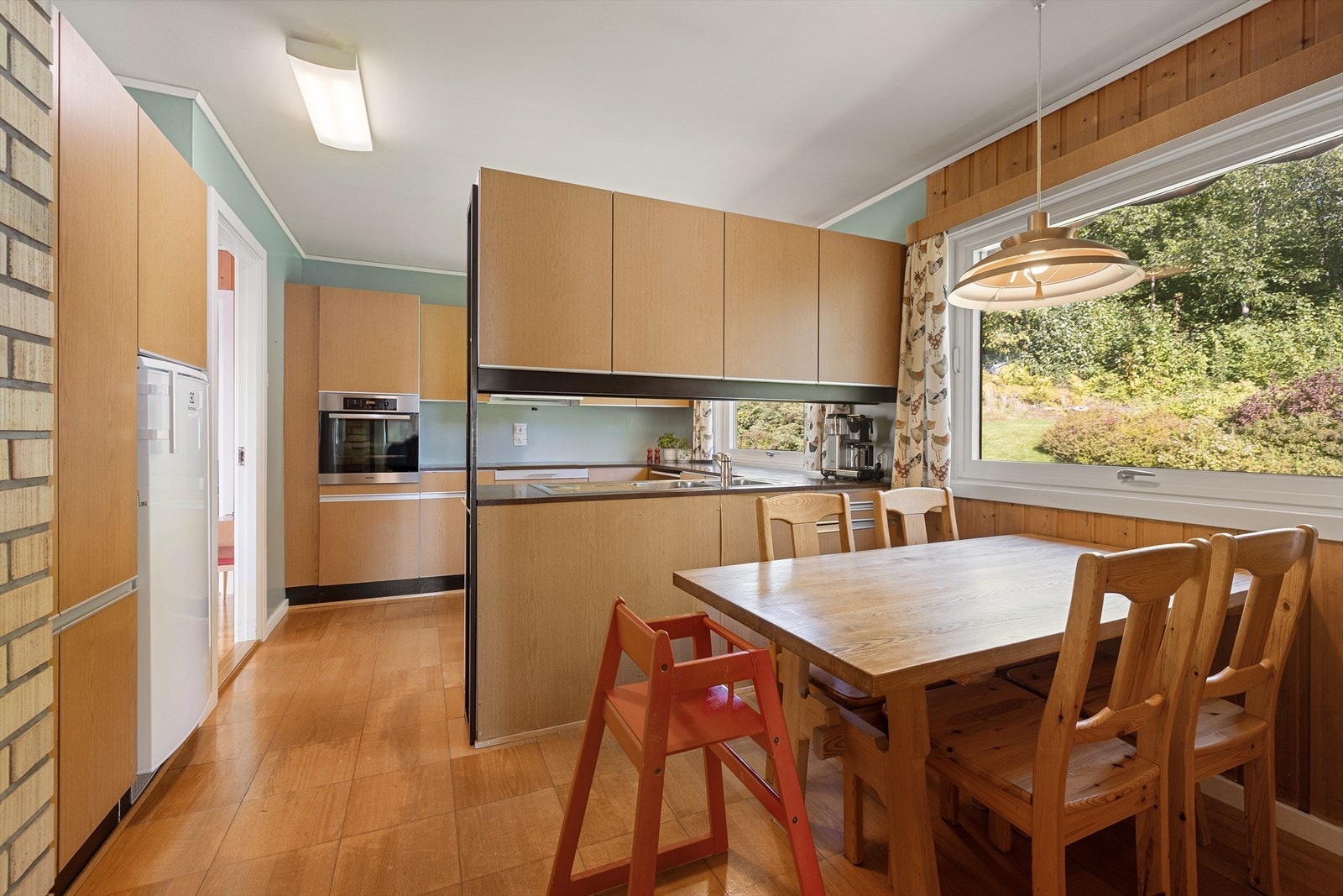 Kjøkkenet er stort og praktisk, og det er en romslig stue og spisestue med direkte adgang til hagen og terrassen bak huset. Galleribilde