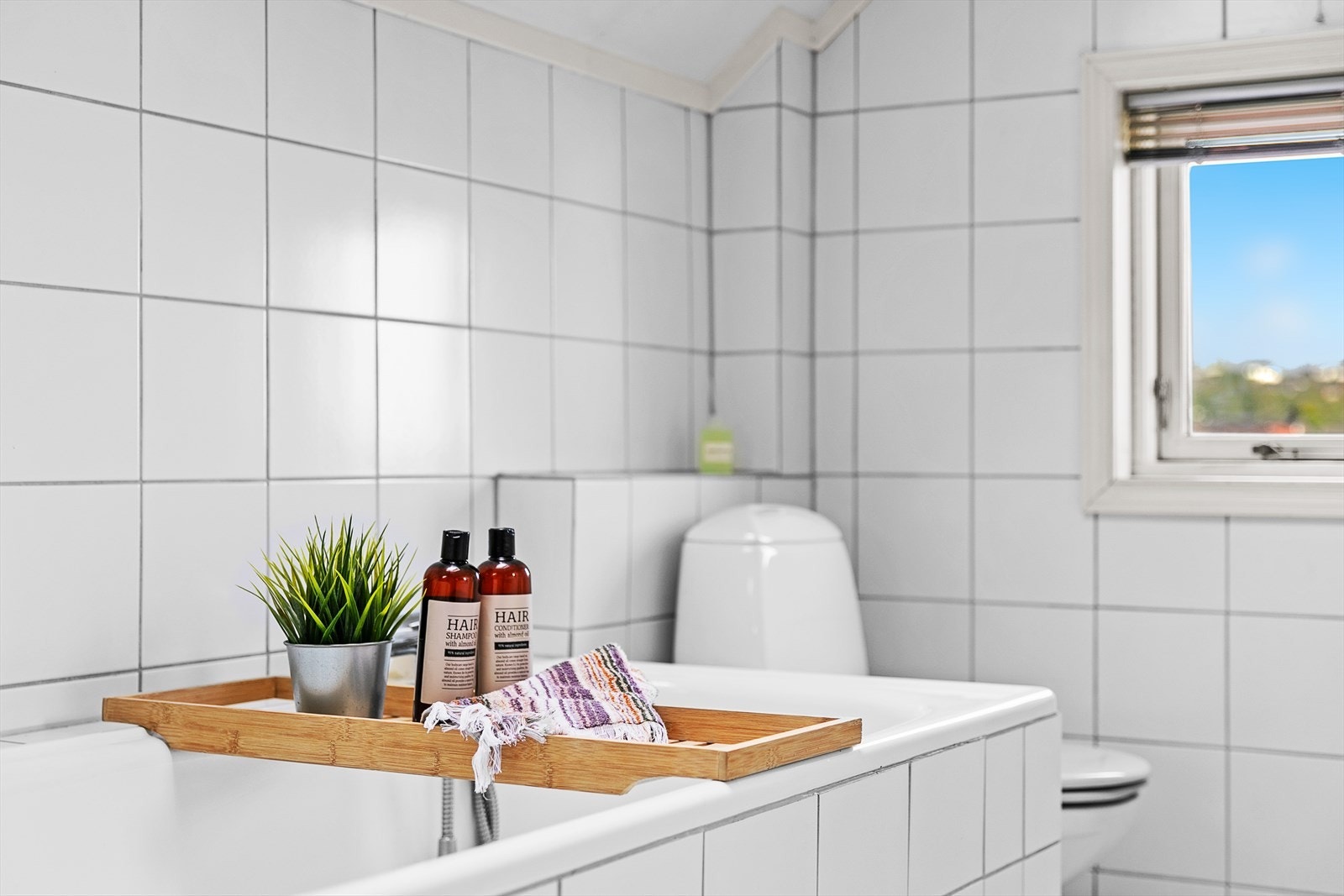 Baderommet inneholder innfliset badekar, innredning med dobbel servant, dusjkabinett og gulvstående wc Galleribilde