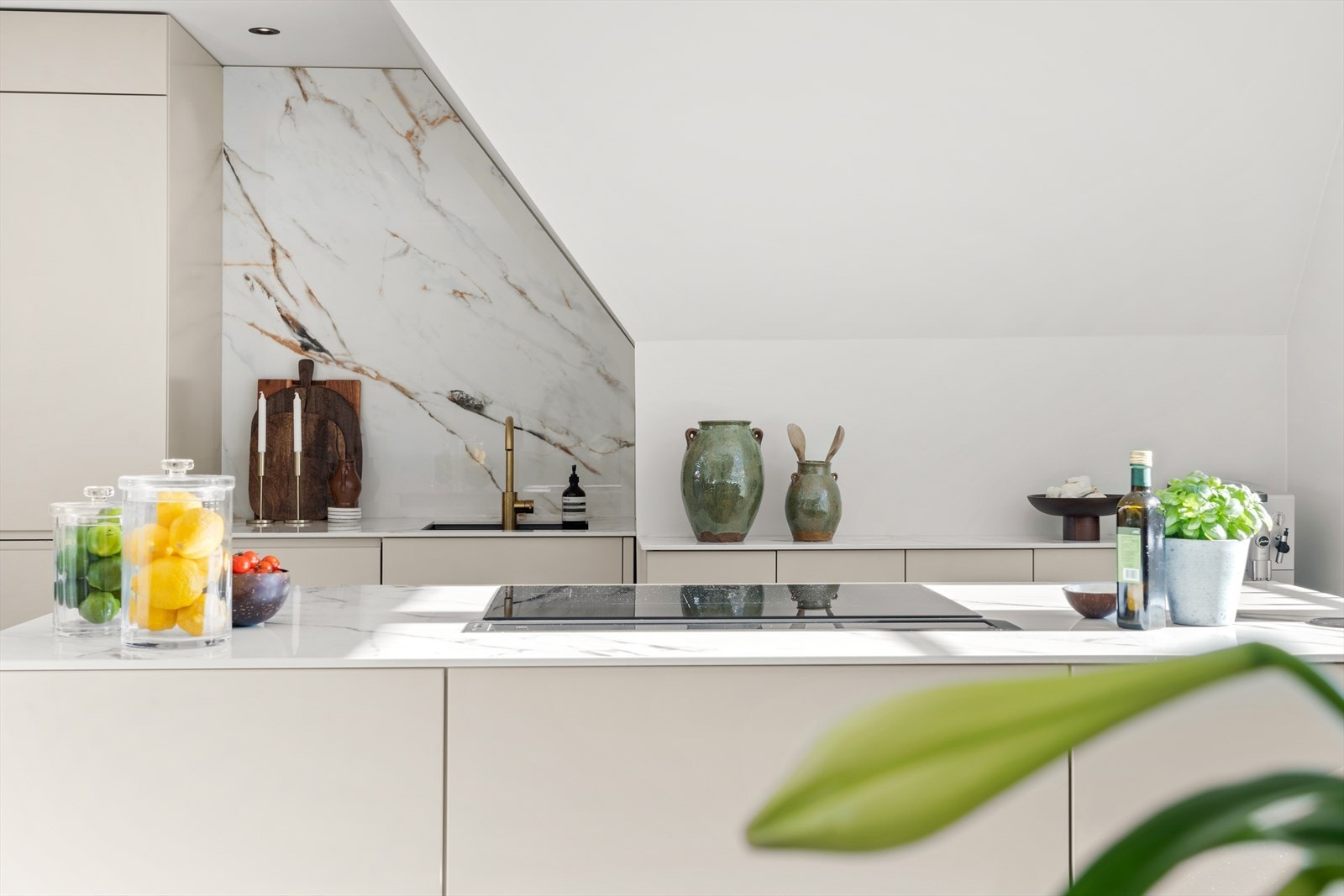 Kjøkkenøy med induksjonstopp og avtrekk som heves/senkes ned i den keramiske benkeplaten. Galleribilde