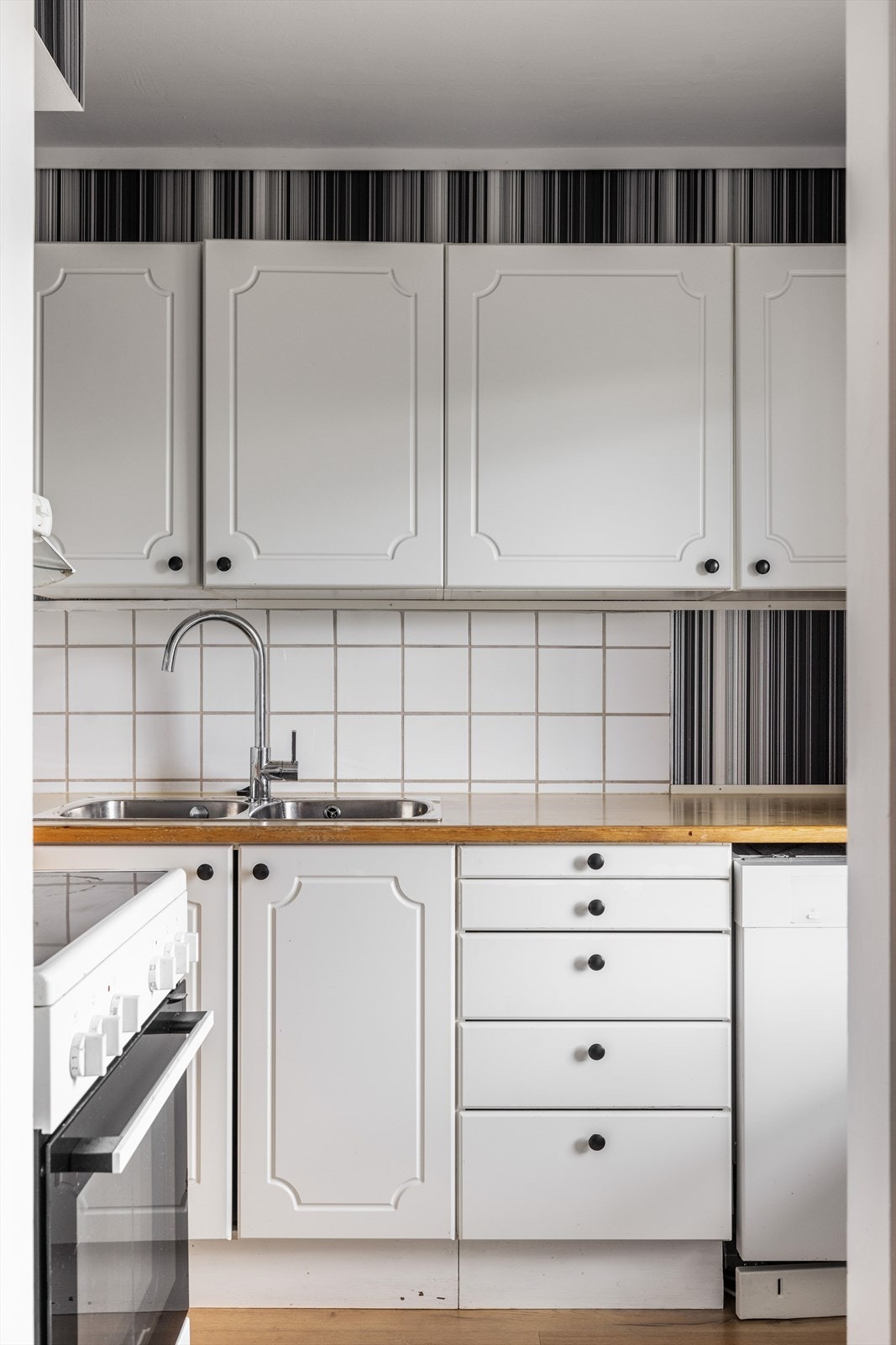 Kjøkken har profilert innredning og laminat benkeplate. Over benkflater er det flis på vegg. Galleribilde