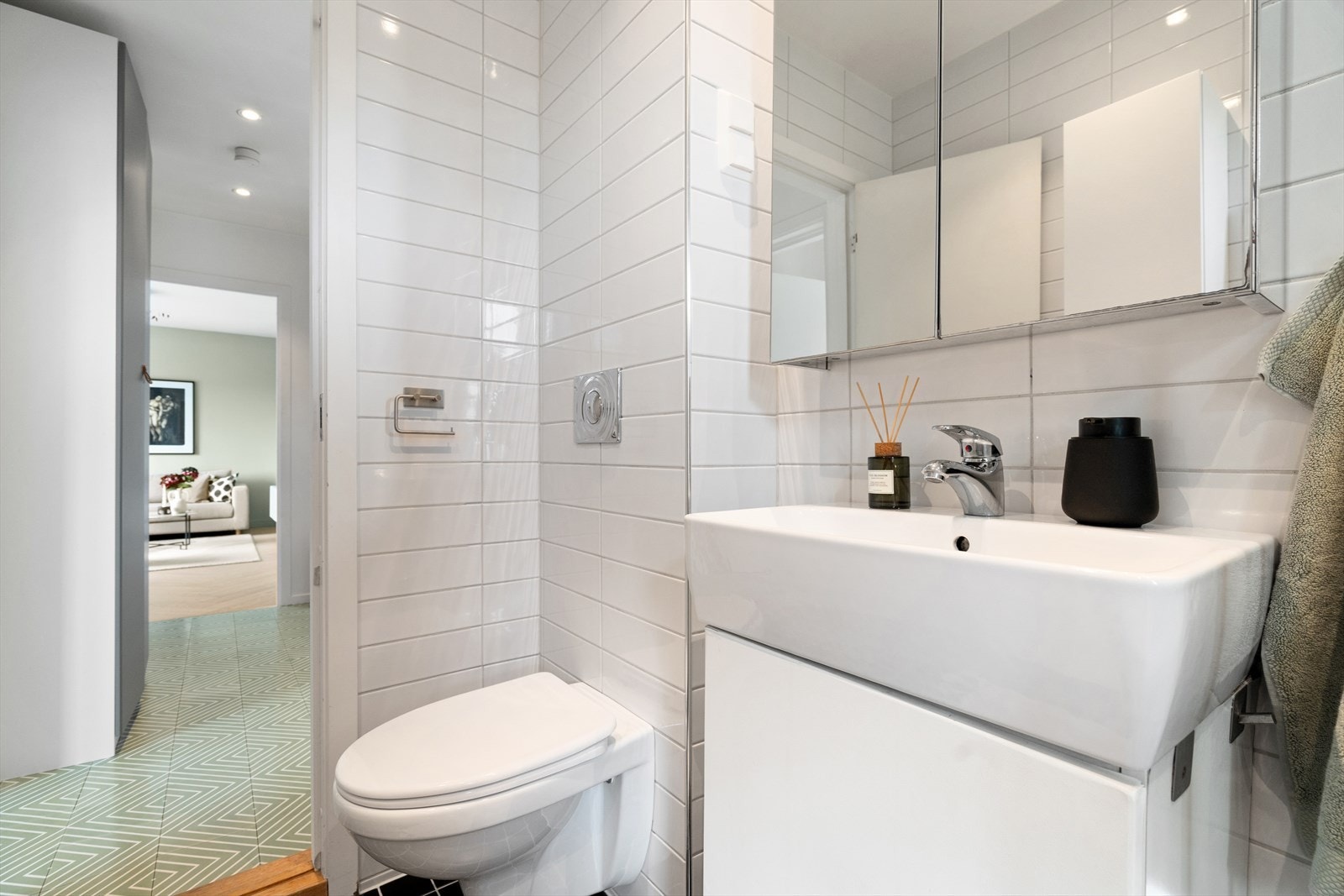 Badet inneholder baderomsinnredning med skap, overlimt servant og speilskap med belysning, veggmontert toalett samt dusjhjørne Galleribilde