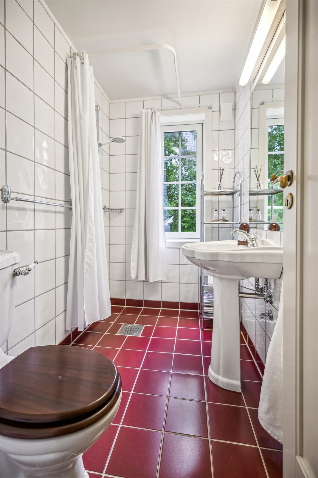 Eldre flislagt baderom i 1. etasje fra 1996 innredet med dusj på gulv, servant og klosett. Galleribilde