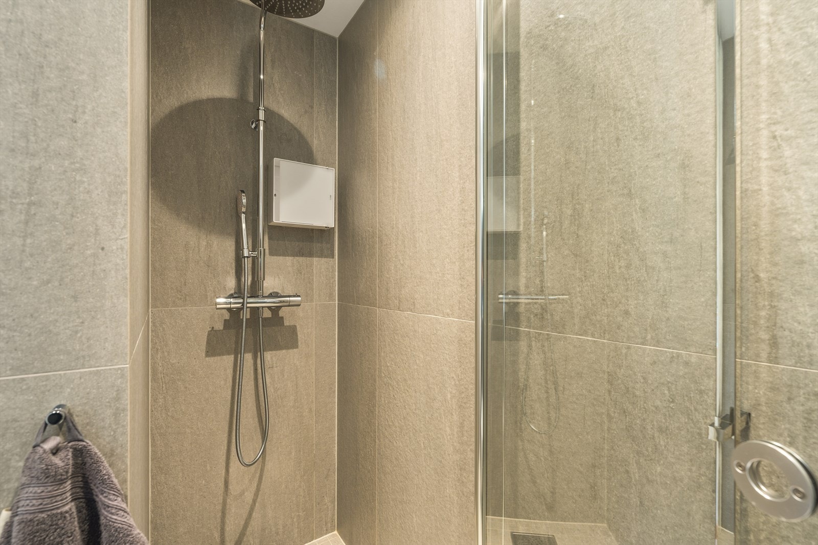Badet er lekkert innredet med stor dusj, servantskap og vegghengt toalett. Galleribilde
