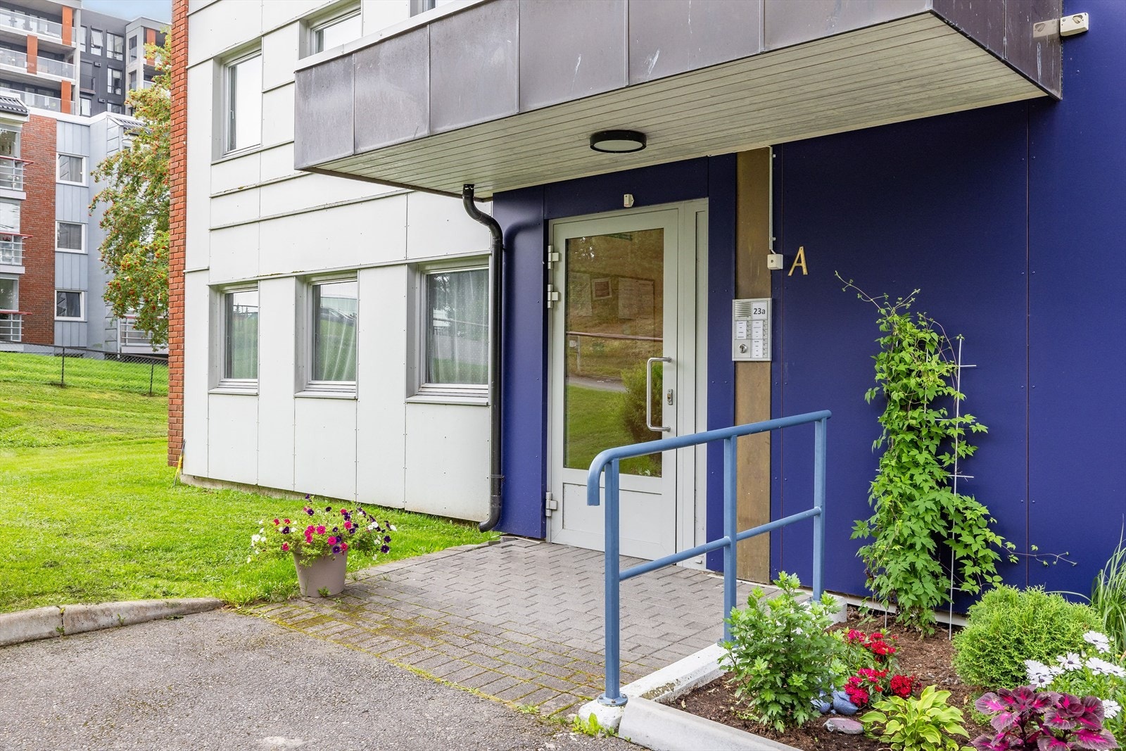 Hyggelig overbygget inngangsparti med belegningsstein og blomsterbed. Galleribilde