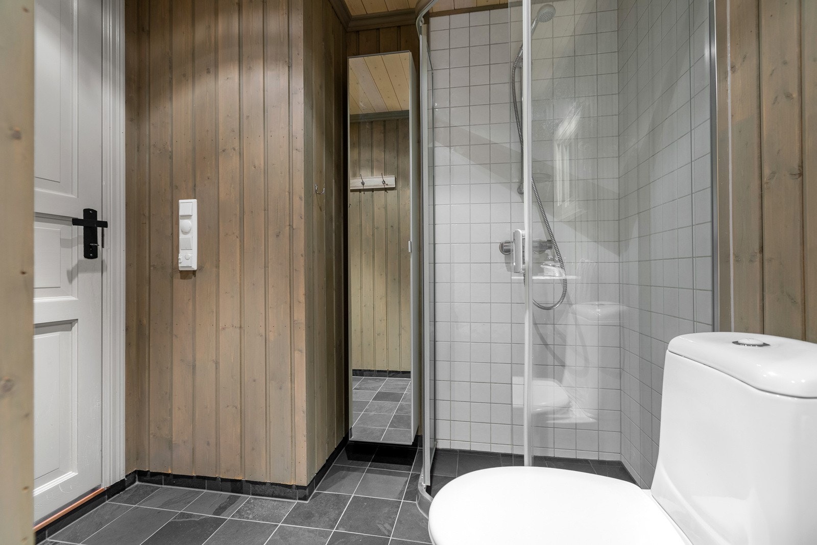 Badet har flislagt gulv og dusjsone, øvrige vegger har behandlet panel. Galleribilde