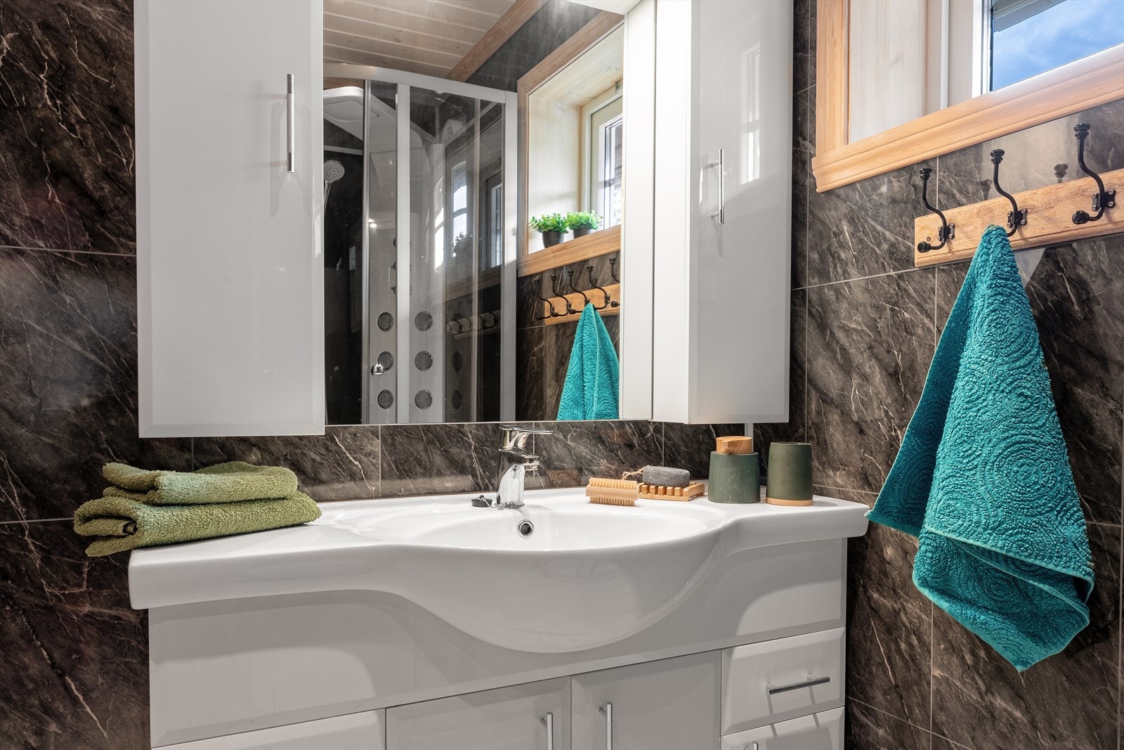 Badet er innredet med servant i heldekkende plate i baderomsmøbler med speil og overlys, veggmontert toalett og dusjkabinett. Det er også varmekabler i gulv. Galleribilde