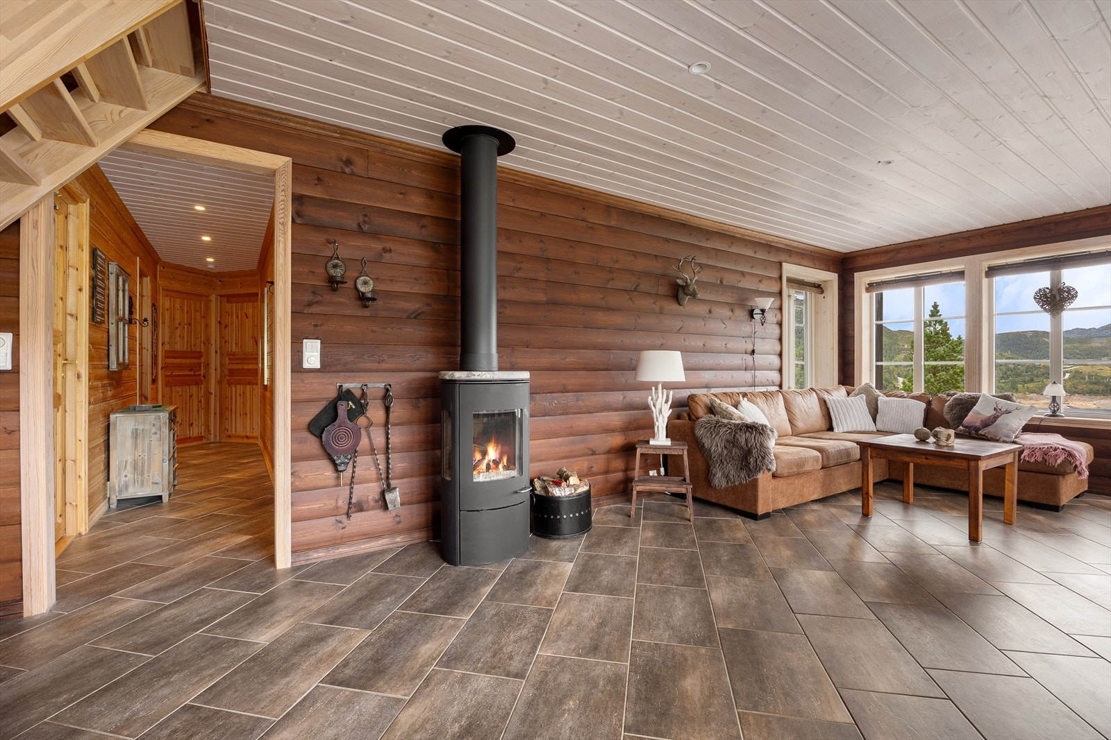 Romslig stue med fliser i gulv og trepaneler på vegger. Galleribilde