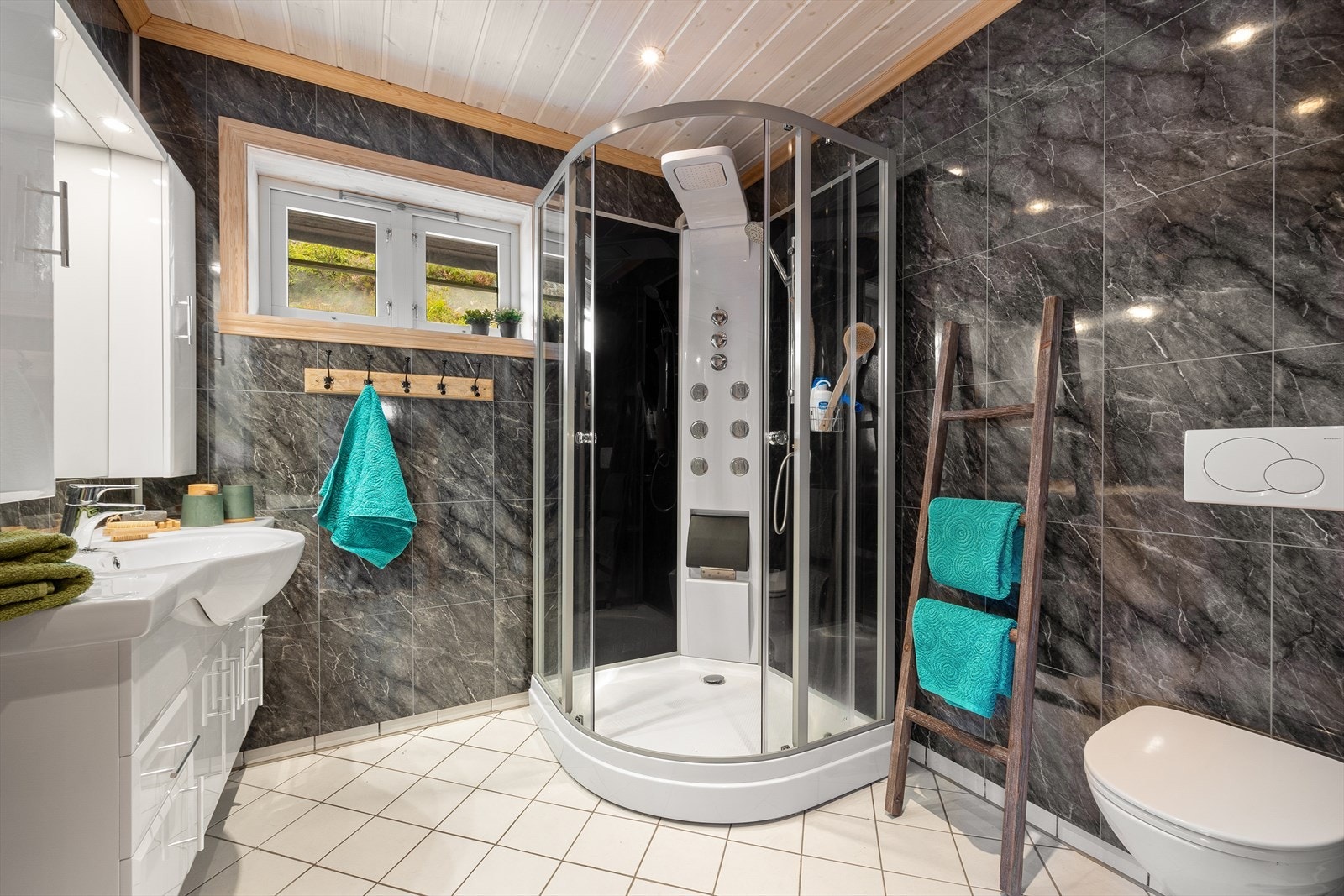 Badet har fliser på gulv og baderomsplater på vegger, samt downlights i tak. Galleribilde