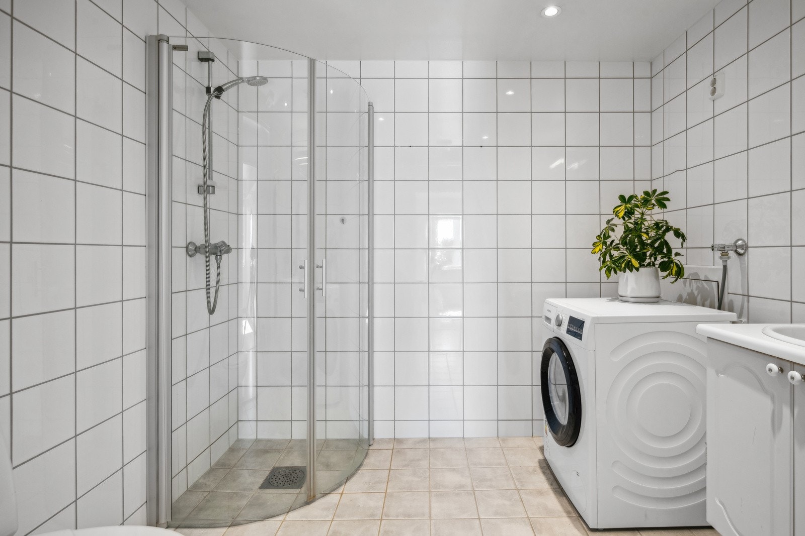 Baderommet inneholder servant med underskap, speil med belysning og stikkontakt, vegghengt toalett og dusj med innfellbare glassdører. Galleribilde