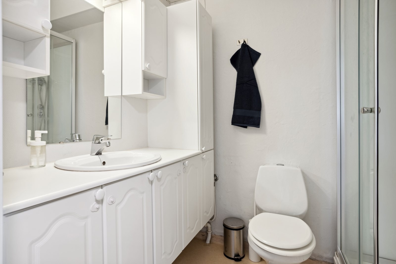 Leilighetens bad inneholder toalett, dusjkabinett og servant med skapinnredning Galleribilde