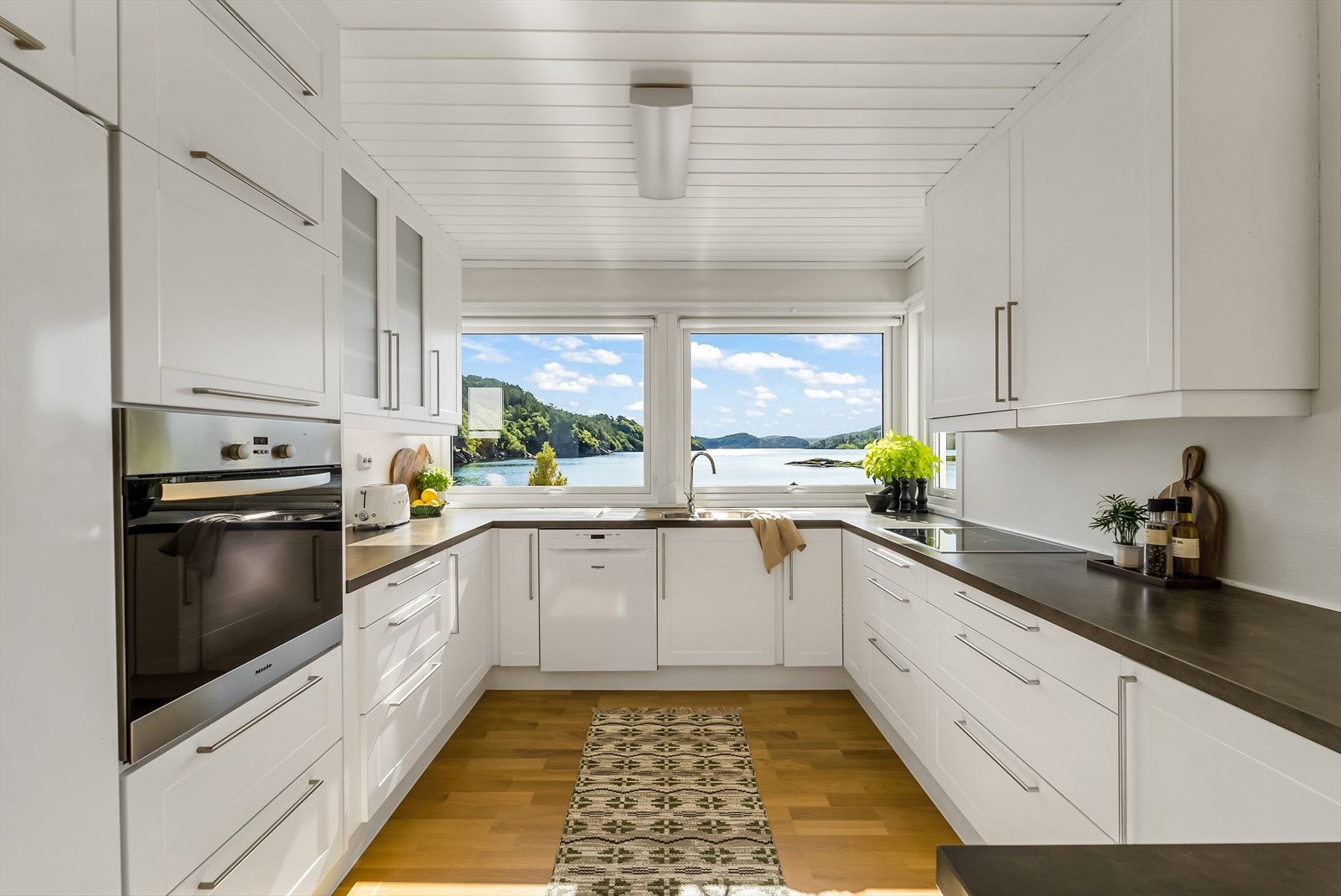 Godt utstyrt kjøkken i hvit profilert innredning med alle hvitevarer integrert med unntak av kjøleskap og fryseskap som er enkeltstående (medfølger). Galleribilde