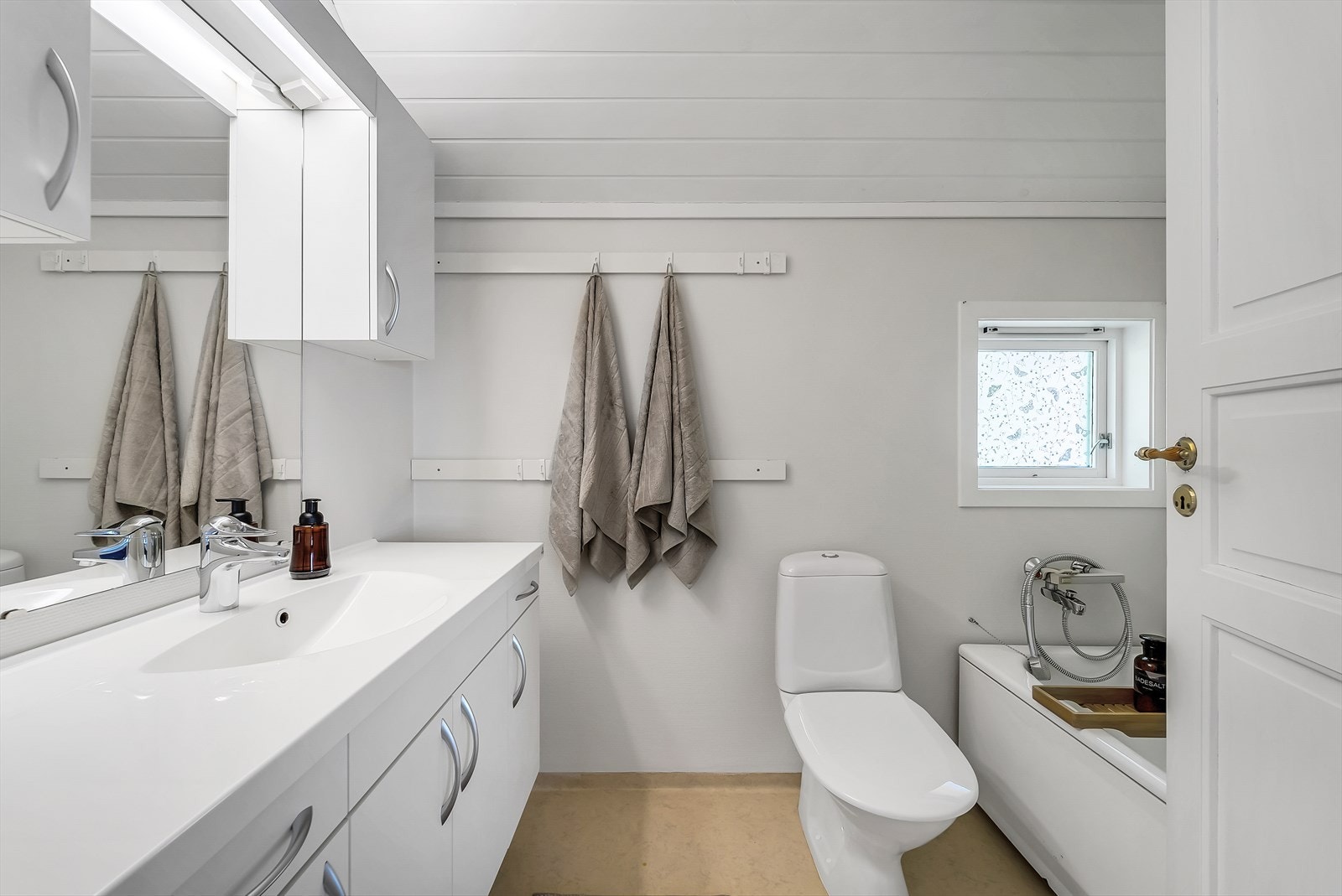 Bad i 2. etasje med belegg på gulv og malte vegger. Badet er innredet med baderomsinnredning. toalett og badekar med hånddusj. Galleribilde