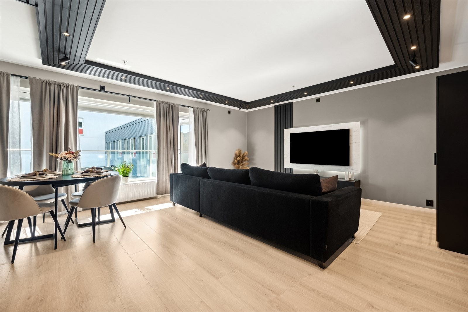 Rommet fylles med naturlig lys gjennom de store vindusflatene. Her er det plass til både TV-hjørne, spiseplass og en komfortabel sofagruppe. Galleribilde