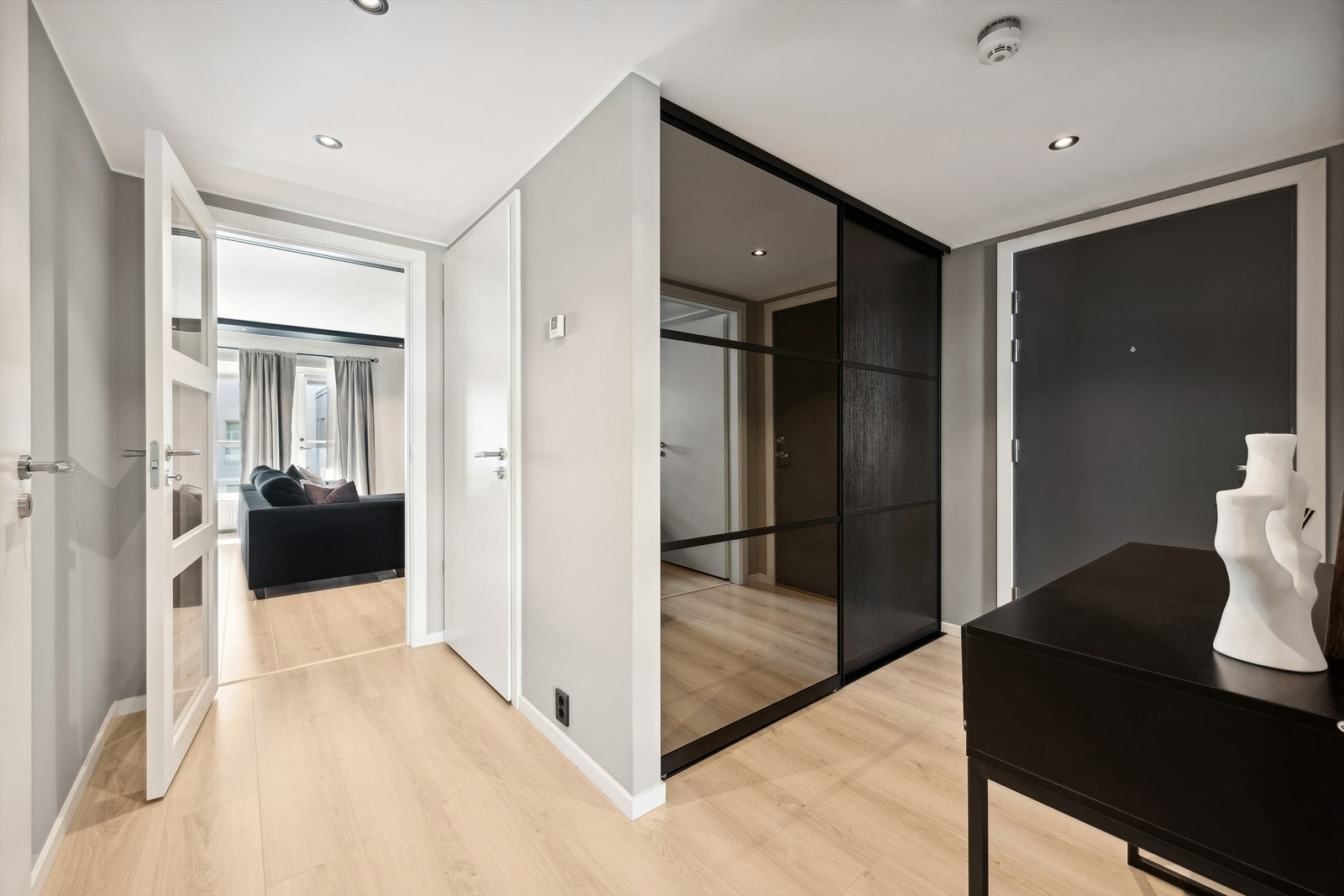 Når du kommer inn, blir du møtt av en innbydende entré med en stilren skyvedørsgarderobe som gir rikelig med plass til å henge fra deg yttertøy og sko. Galleribilde