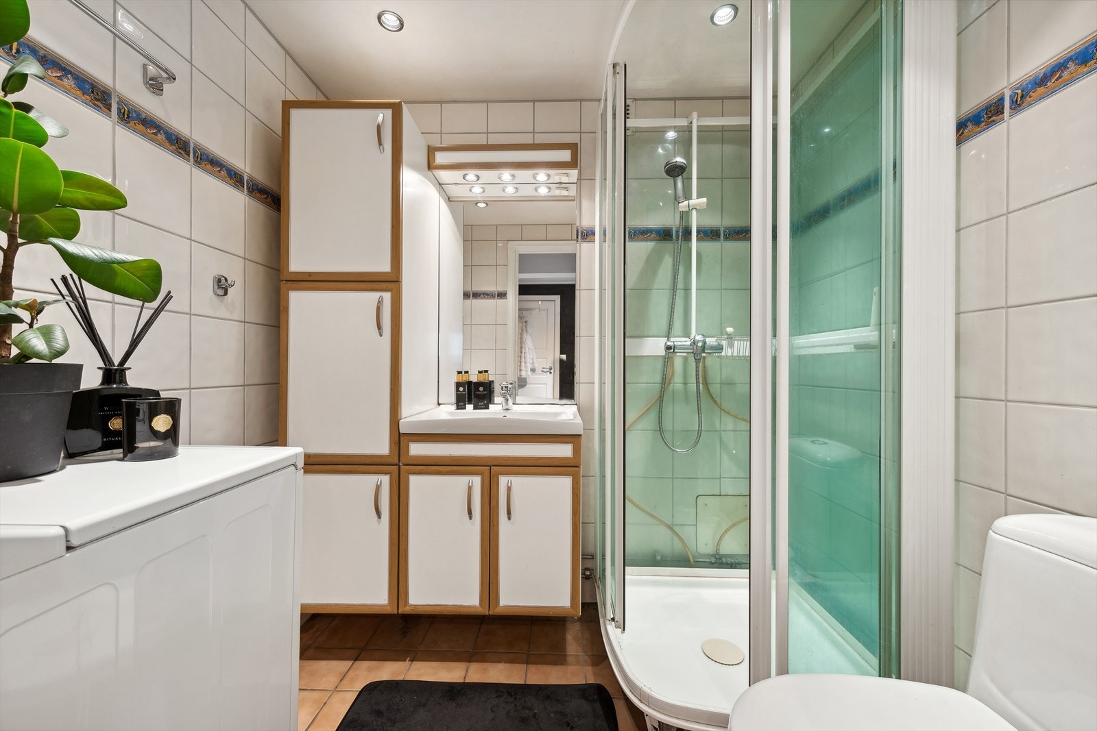 Badet er innredet med dusjkabinett, klosett, servant, servantskap, høyskap, og speil med belysning. Galleribilde