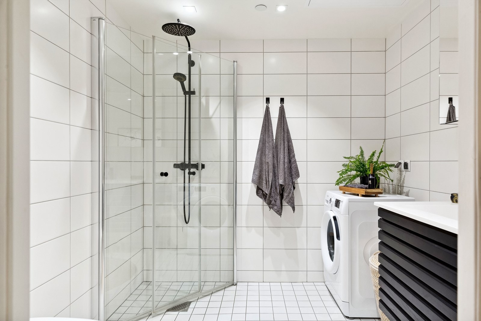 Dusjhjørnet har regnfallsdusj og plassbesparende, innfellbare glassdører. Badsinnredningen er levert fra HTH. Galleribilde