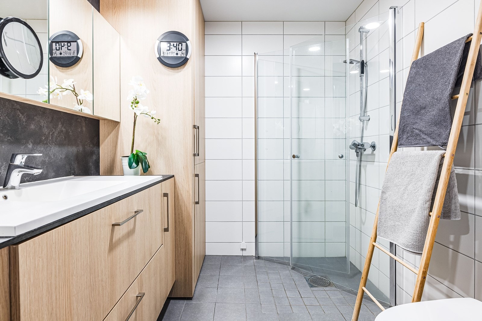 Leiligheten har et lyst og moderne baderom fra byggeåret 2021. Baderommet har grå fliser på gulv med gulvvarme, hvite fliser på veggene, downlights i himlingen og balansert ventilasjon. Galleribilde