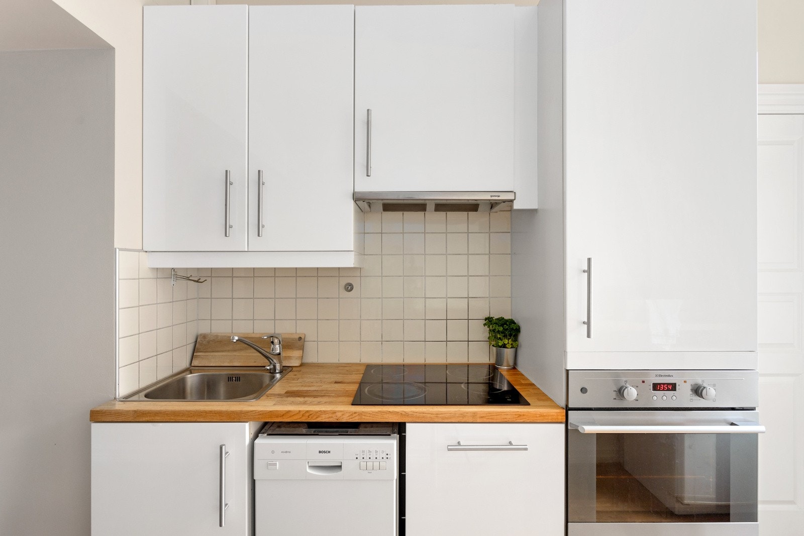 Nedfelt oppvaskkum med ett-greps kjøkkenarmatur, benkeskapsbelysning og stikkontakter over kjøkkenbenk. Galleribilde