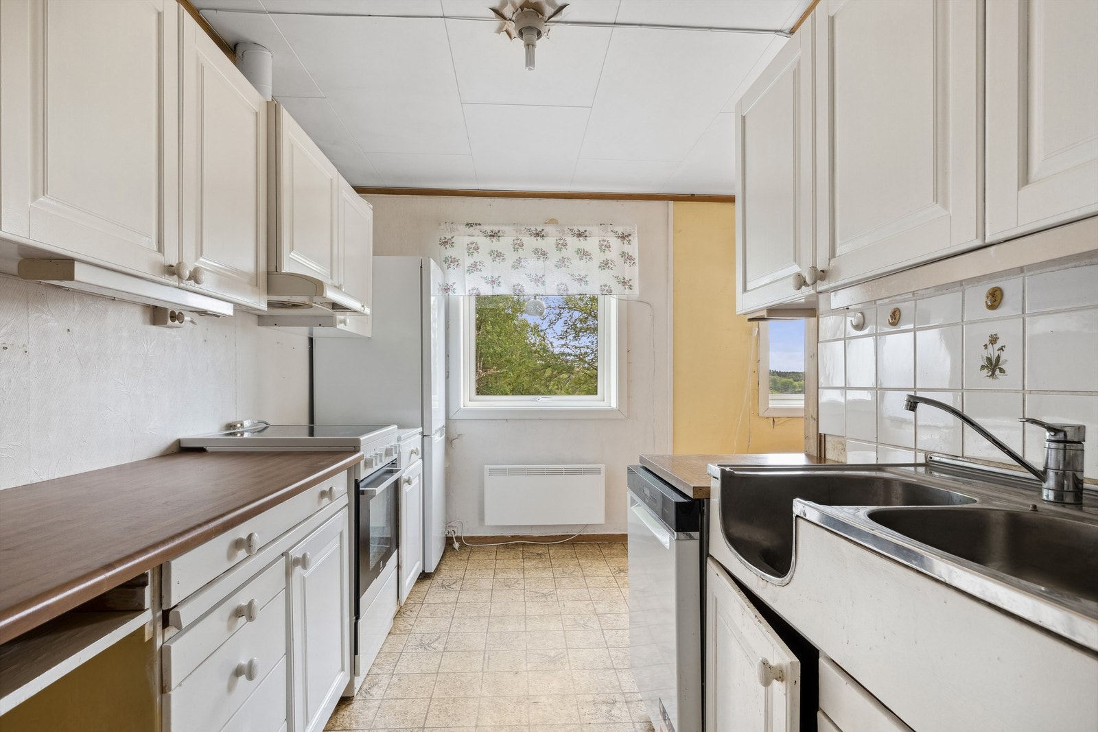 Kjøkkenet har skapinnredning med malte fronter i heltre furu og laminat benkeplate Galleribilde