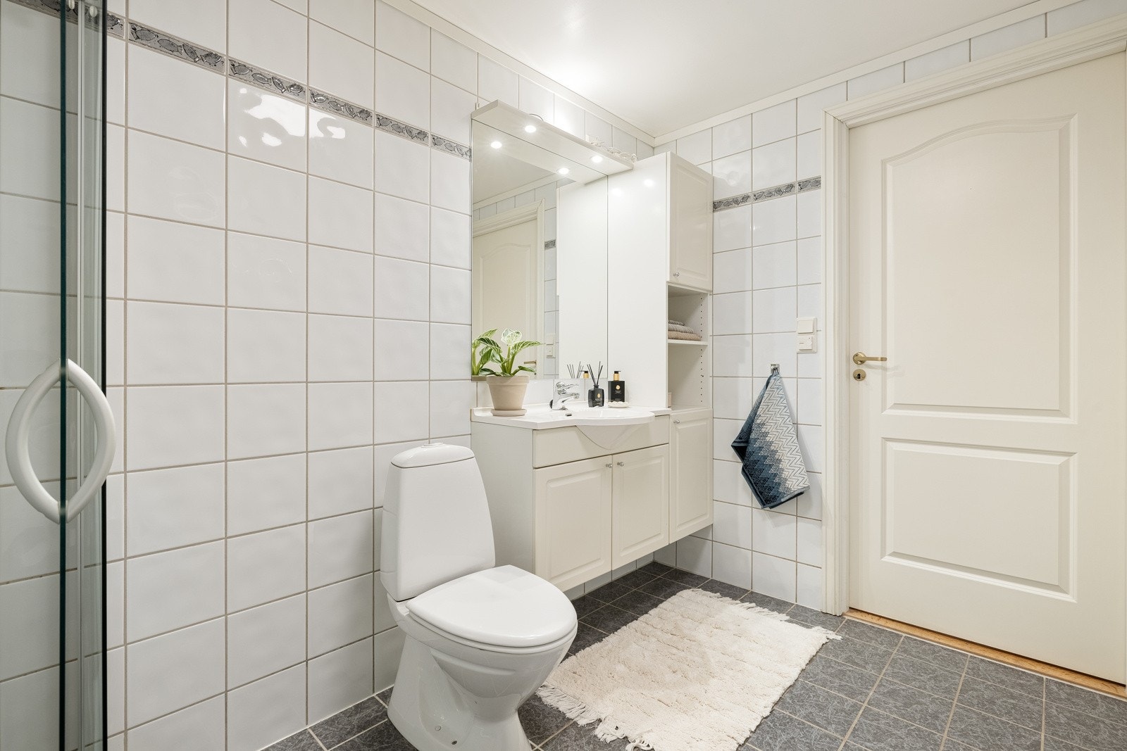 Badet er innredet med baderomsmøbel, dusjhjørne og toalett. Det er også opplegg for vaskemaskin og tørketrommel. Galleribilde