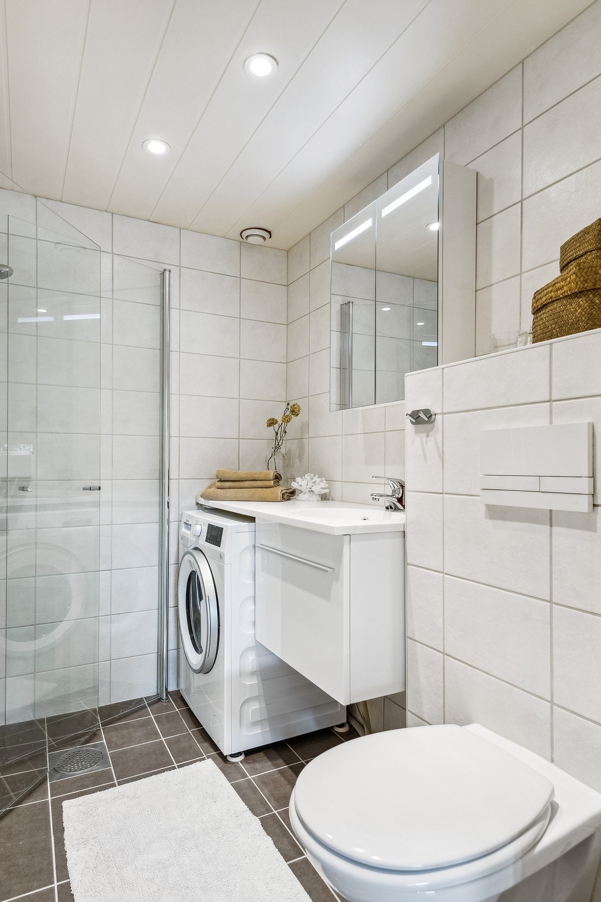 Badet har vegghengt klosett, dusjhjørne og opplegg for vaskemaskin Galleribilde