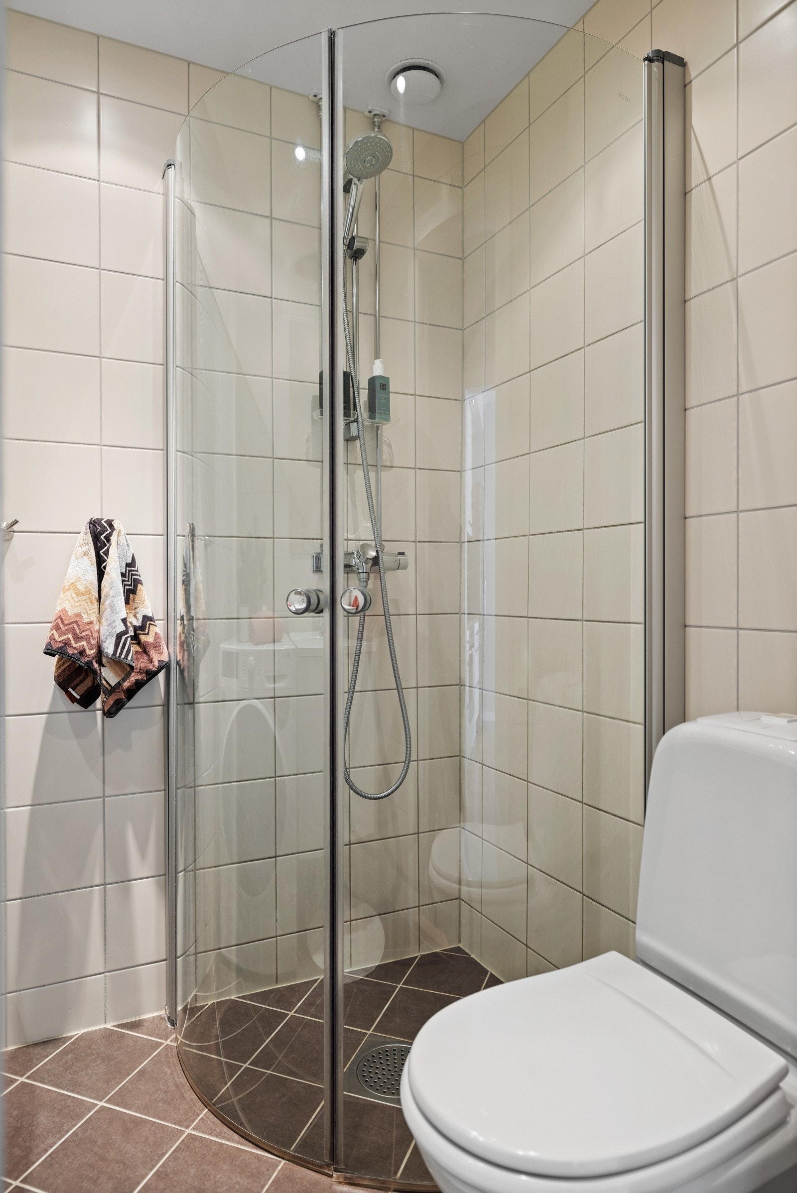 Badet har gulvstående toalett og vegghengte dusjdører i glass. Galleribilde