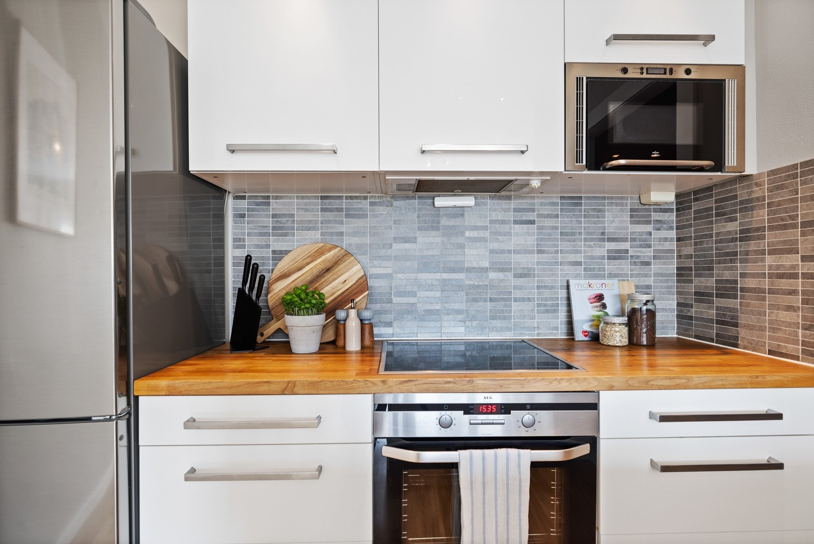 Pent kjøkken fra 2010 med hvite glatte fronter og heltre benkeplate. Galleribilde