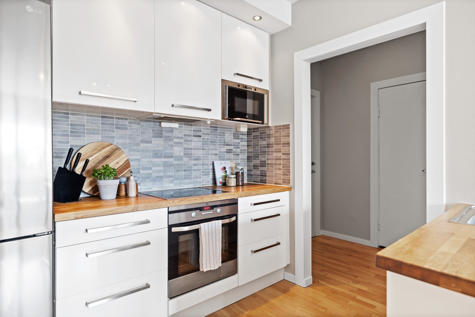 Kjøkkenet har integrerte hvitevarer med innfelt platetopp i benkeplate, oppvaskmaskin og komfyr. Opplegg for frittstående kjøl/frys. Galleribilde