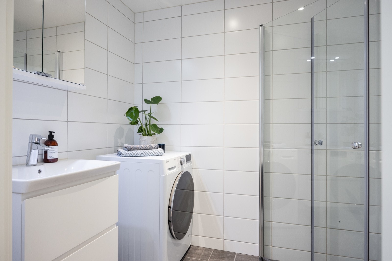 Innredningen på badet består av vegghengt toalett, enkel servant og dusjnisje med svingbare glassdører Galleribilde