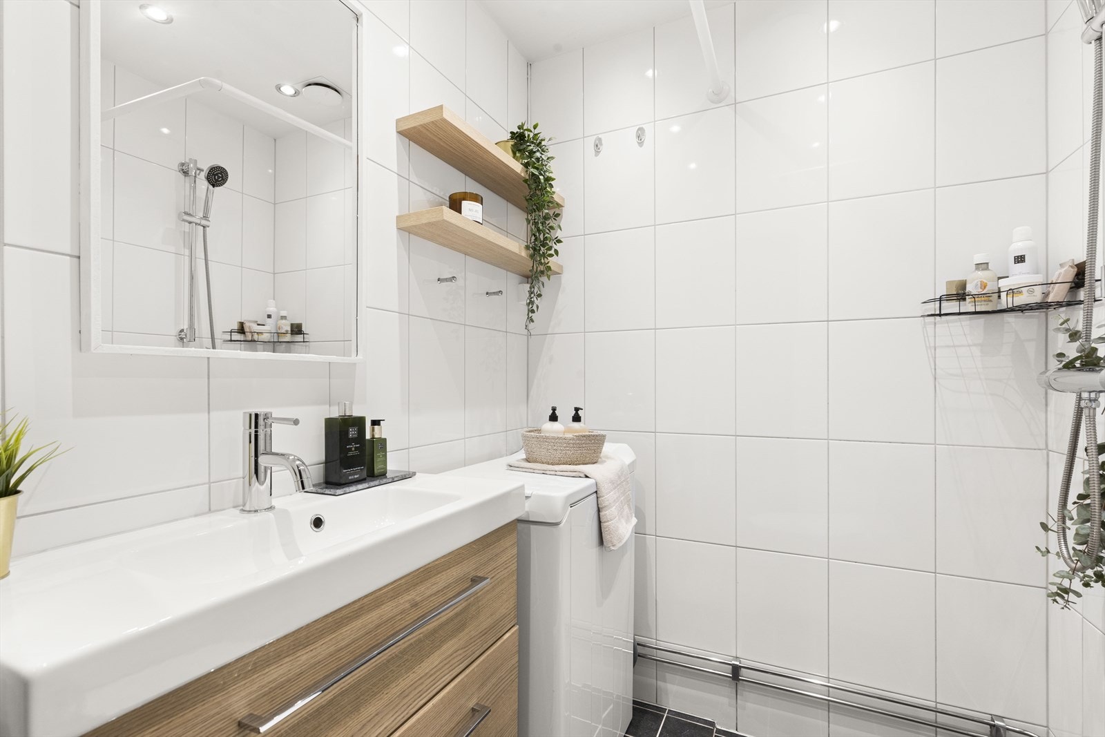 Badet er utstyrt med et gulvmontert toalett, en servantinnredning et dusjhjørne med oppheng for dusjforheng samt opplegg for vaskemaskin. Galleribilde